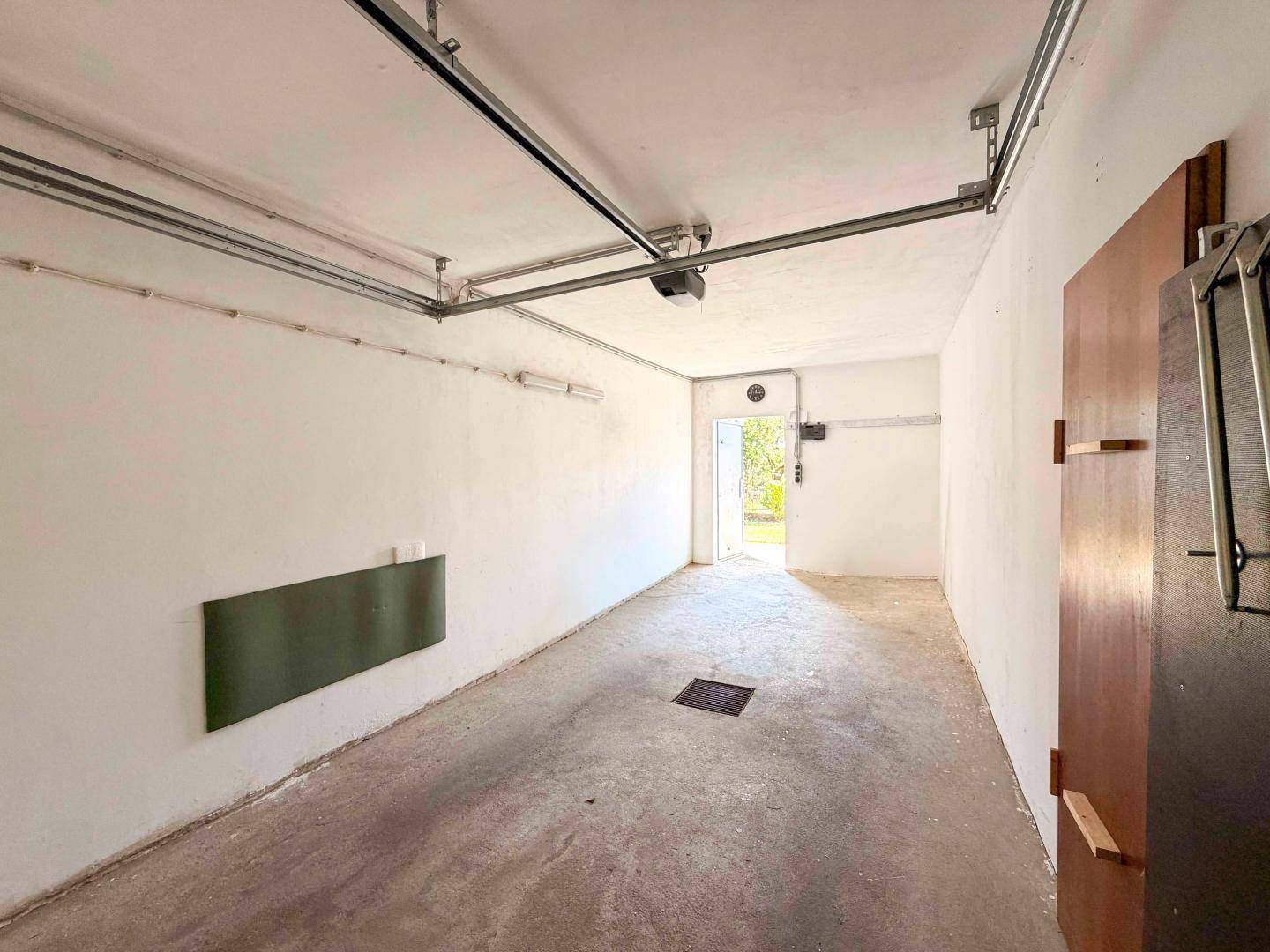 Geräumige Garage mit Betonboden und weiß gestrichenen Wänden, unmöbliert.