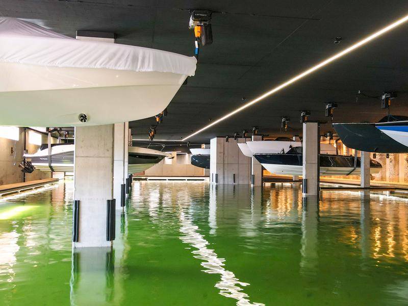Bootslagerhalle mit hängenden Booten über dem Wasserbecken und Betonpfeilern.