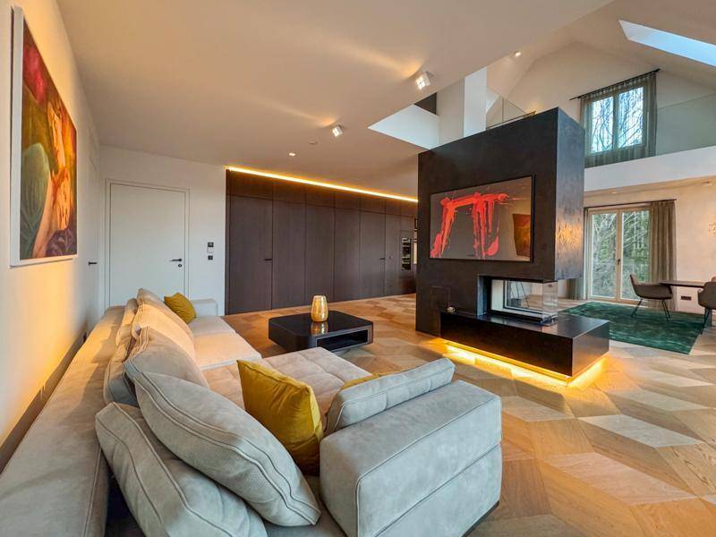 Stilvoller Wohnbereich mit bequemer Couch, modernem Kamin und Blick auf die offene Küche.