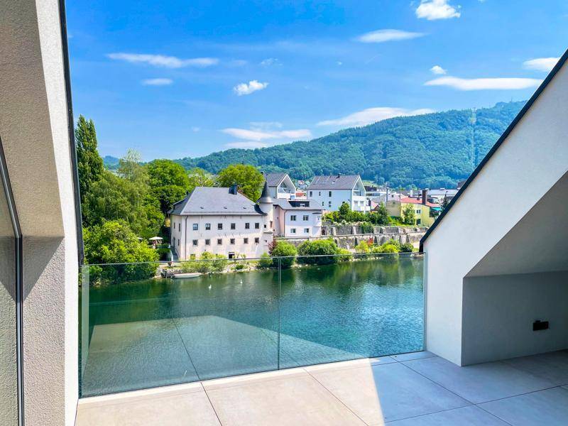 Geräumige Terrasse mit Glasbrüstung und weitem Blick auf den See und die umliegende Landschaft.