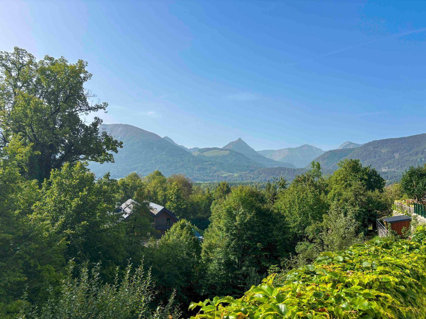 Panoramablick auf die majestätischen Berge und die umliegende grüne Landschaft unter blauem Himmel.