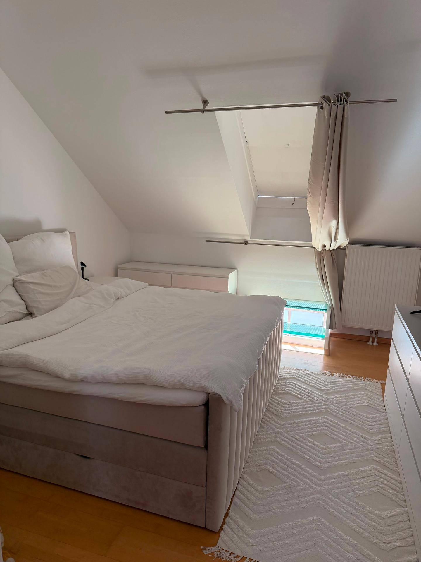 Schlafzimmer im Dachgeschoss mit Dachschräge, großem Bett und Holzboden.