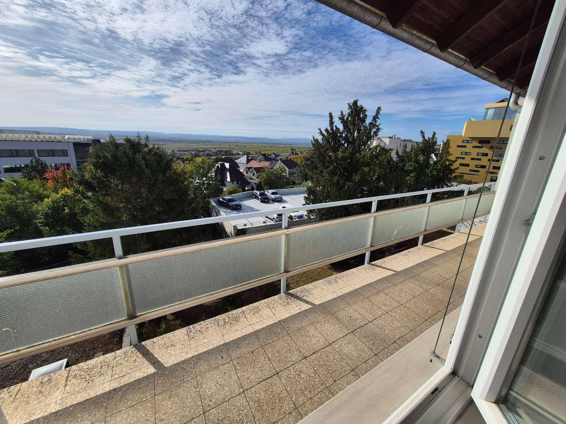 Langer Balkon mit Fliesenboden und weitem Blick über die Landschaft und die Stadt.