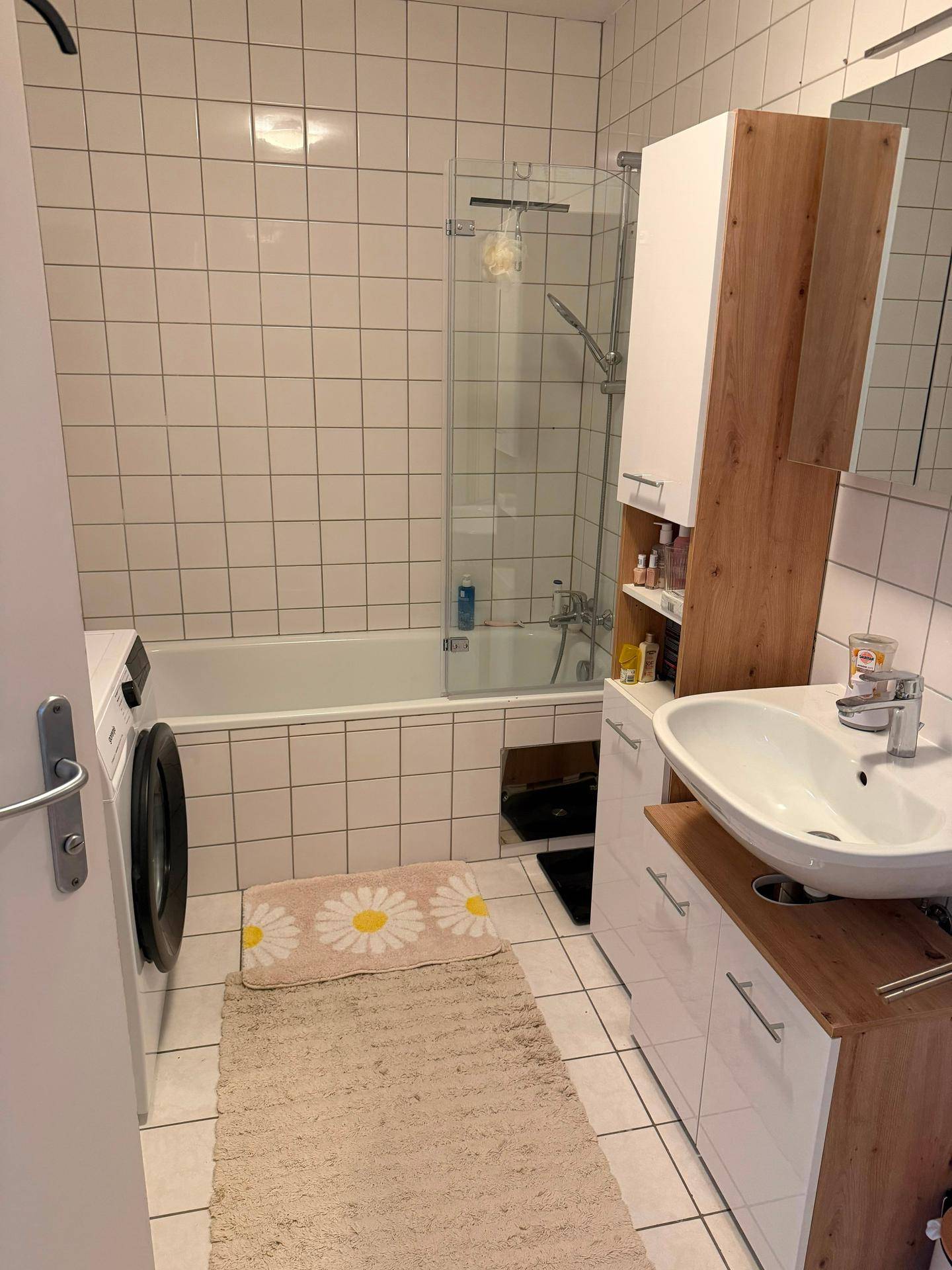 Badezimmer mit Badewanne, Duschabtrennung, Waschbecken und Waschmaschine.