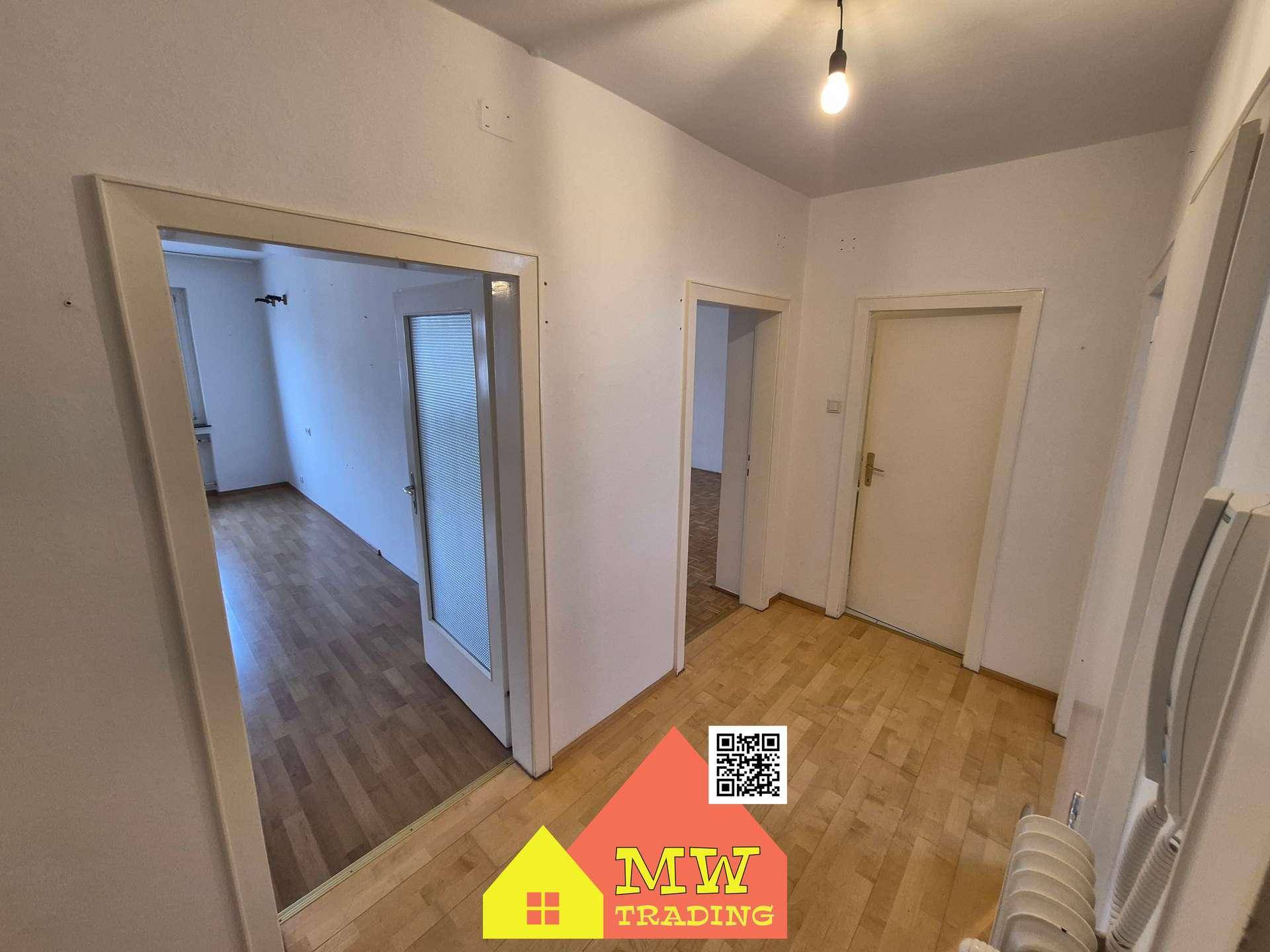 Geräumiger Flur mit Holzboden und einer Glastür, die zu einem weiteren Zimmer führt.