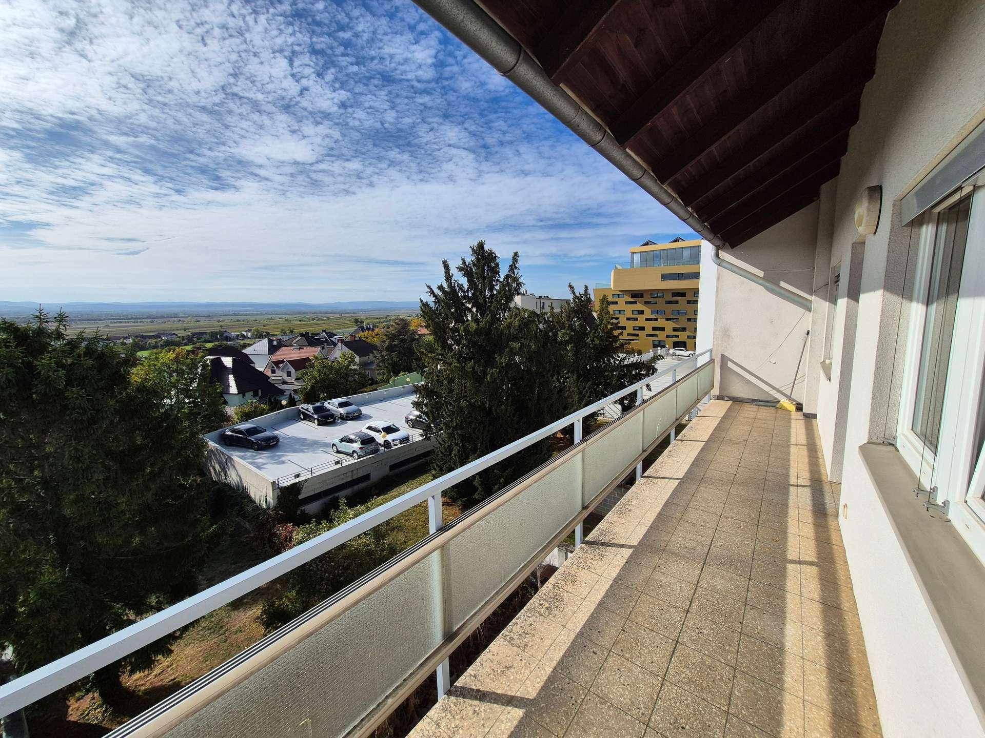 Geräumiger Balkon mit Fliesenboden und Panoramablick auf die Umgebung unter blauem Himmel.