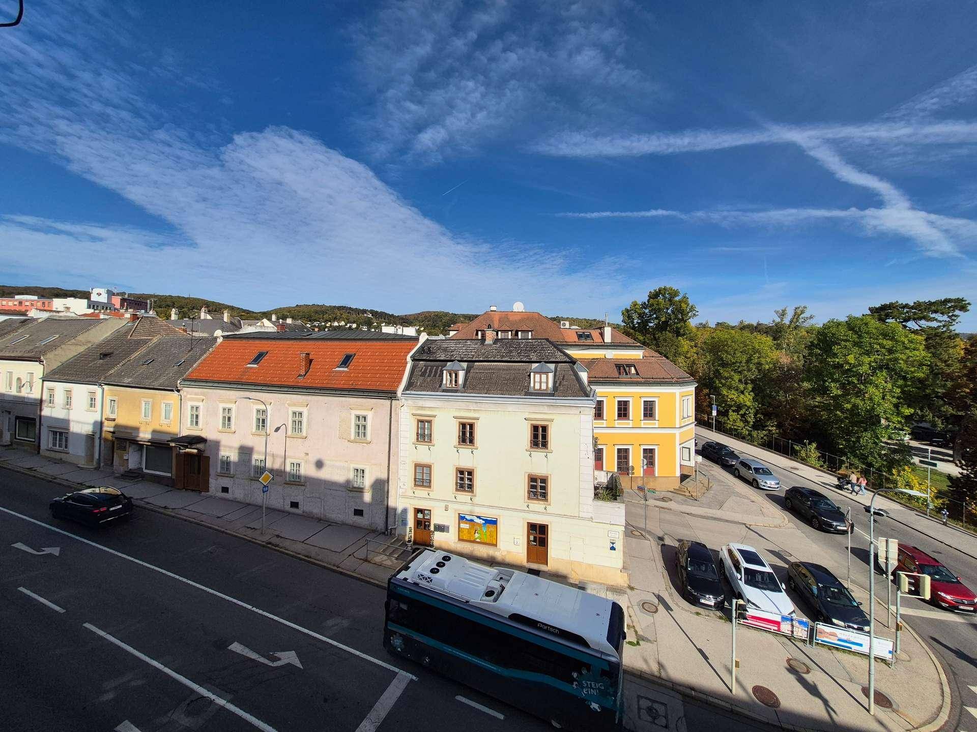 Panoramablick auf die Stadt mit einer Reihe von Gebäuden, einer Straße und einem weiten Himmel.