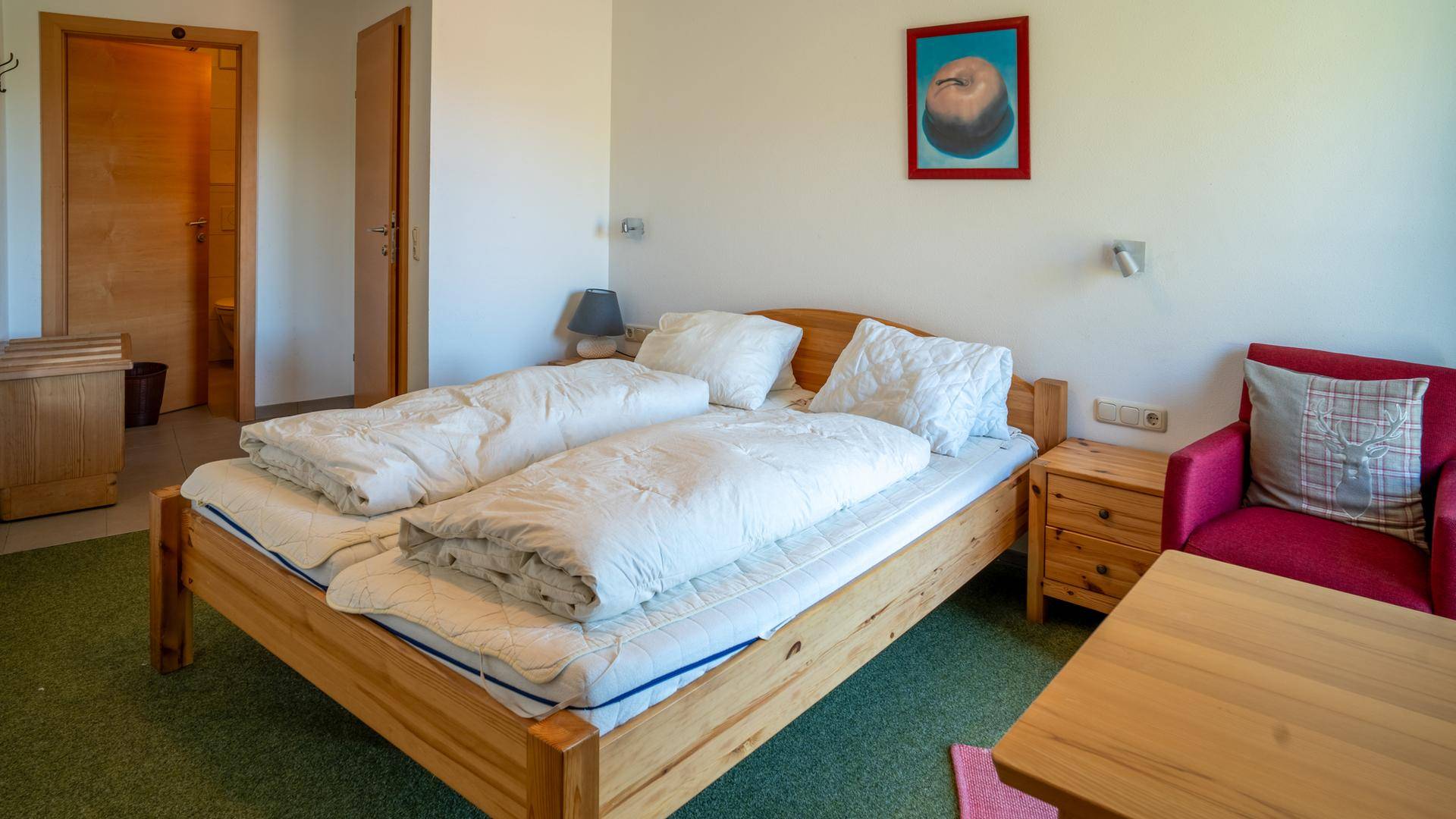 Gemütliches Schlafzimmer mit Doppelbett, Teppichboden und einfacher Einrichtung.