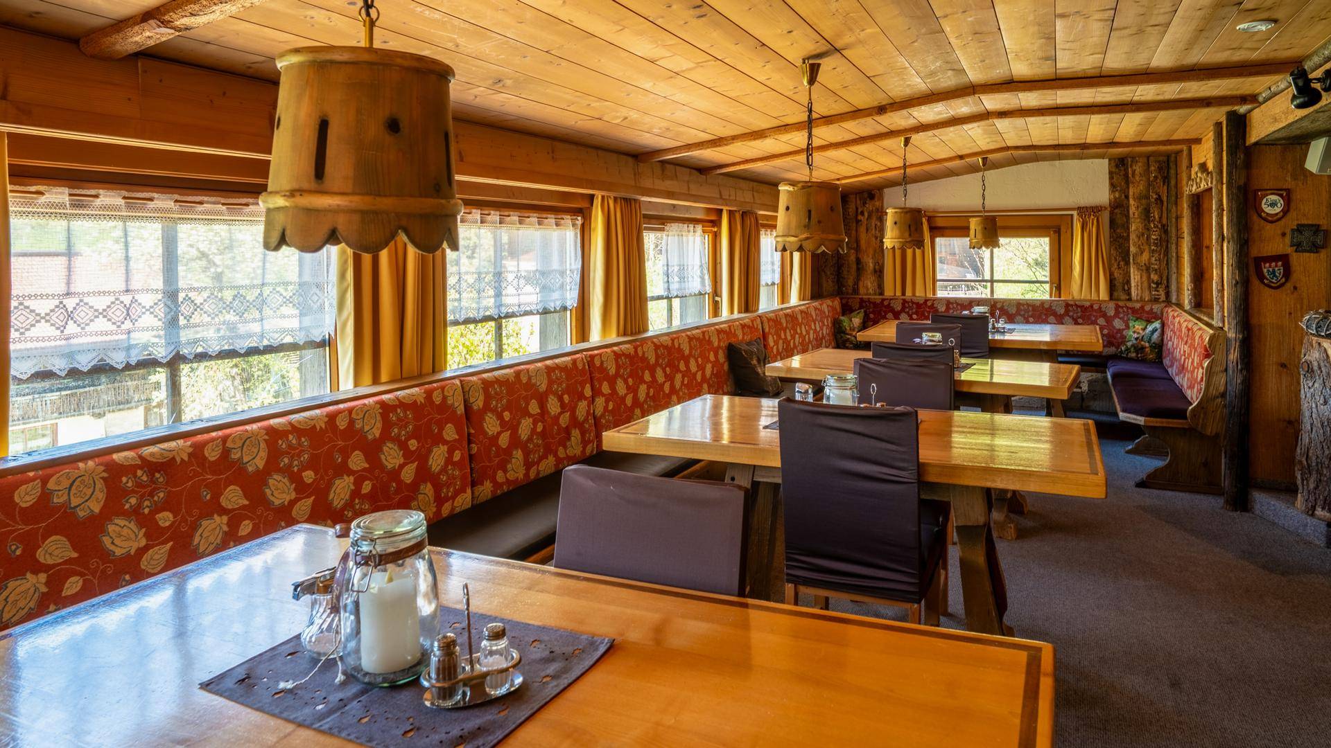 Gemütlicher Speisesaal mit Holztischen, gepolsterten Bänken und alpiner Atmosphäre.