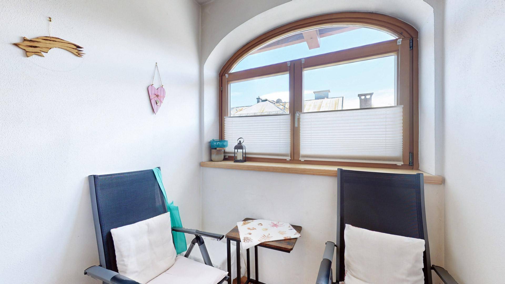 Gemütlicher Wintergarten mit Sitzgelegenheiten und einem großen Bogenfenster, ideal zum Entspannen.
