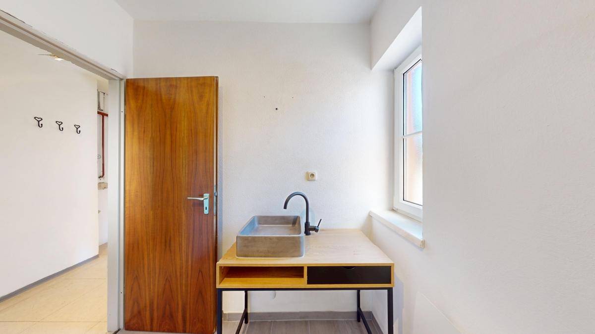 Helles Badezimmer mit modernem Waschbecken auf einem Holzunterschrank und Fenster für Tageslicht.
