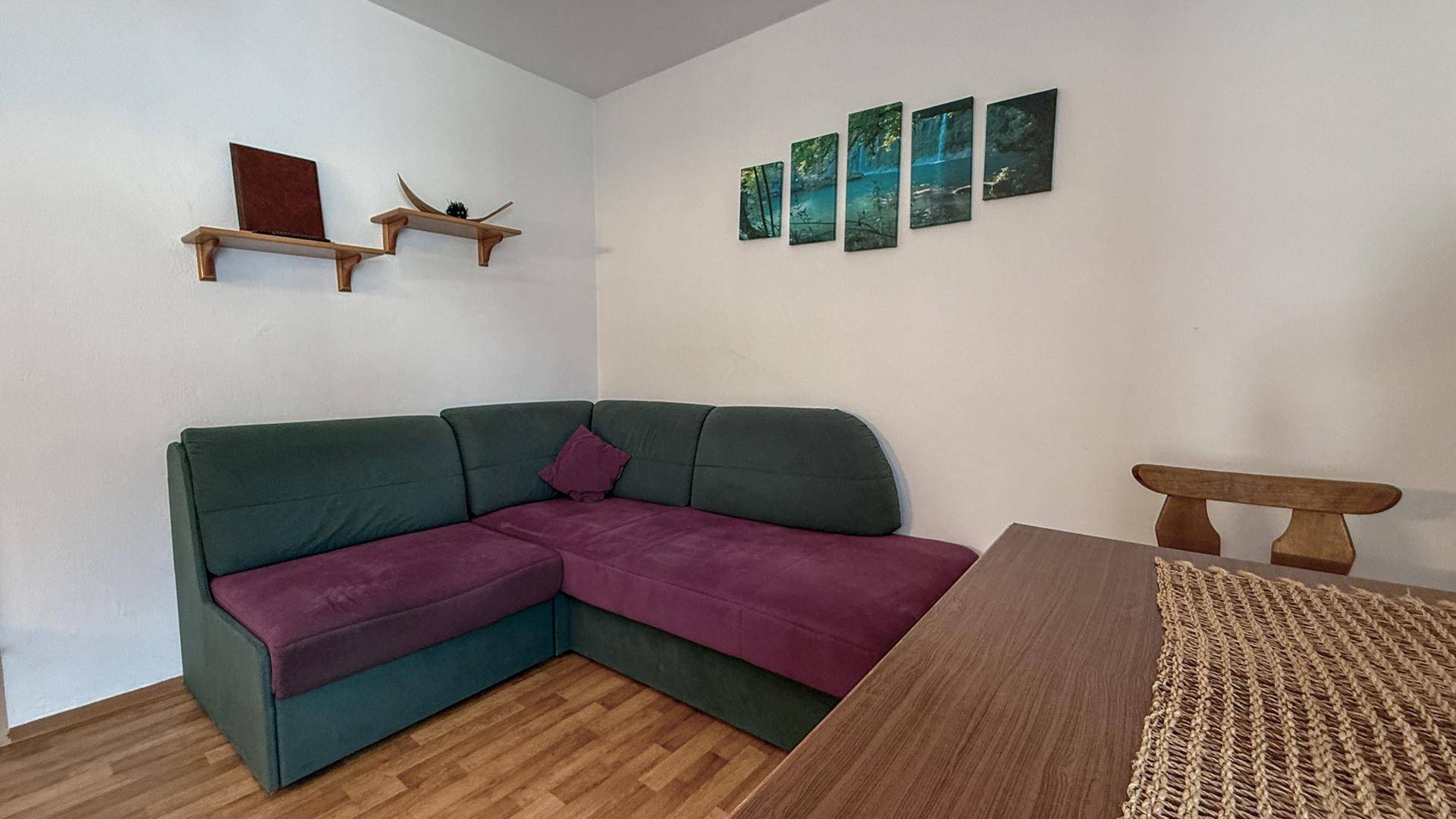 Gemütliches Wohnzimmer mit Ecksofa, Holztisch und dekorativen Wandbildern.