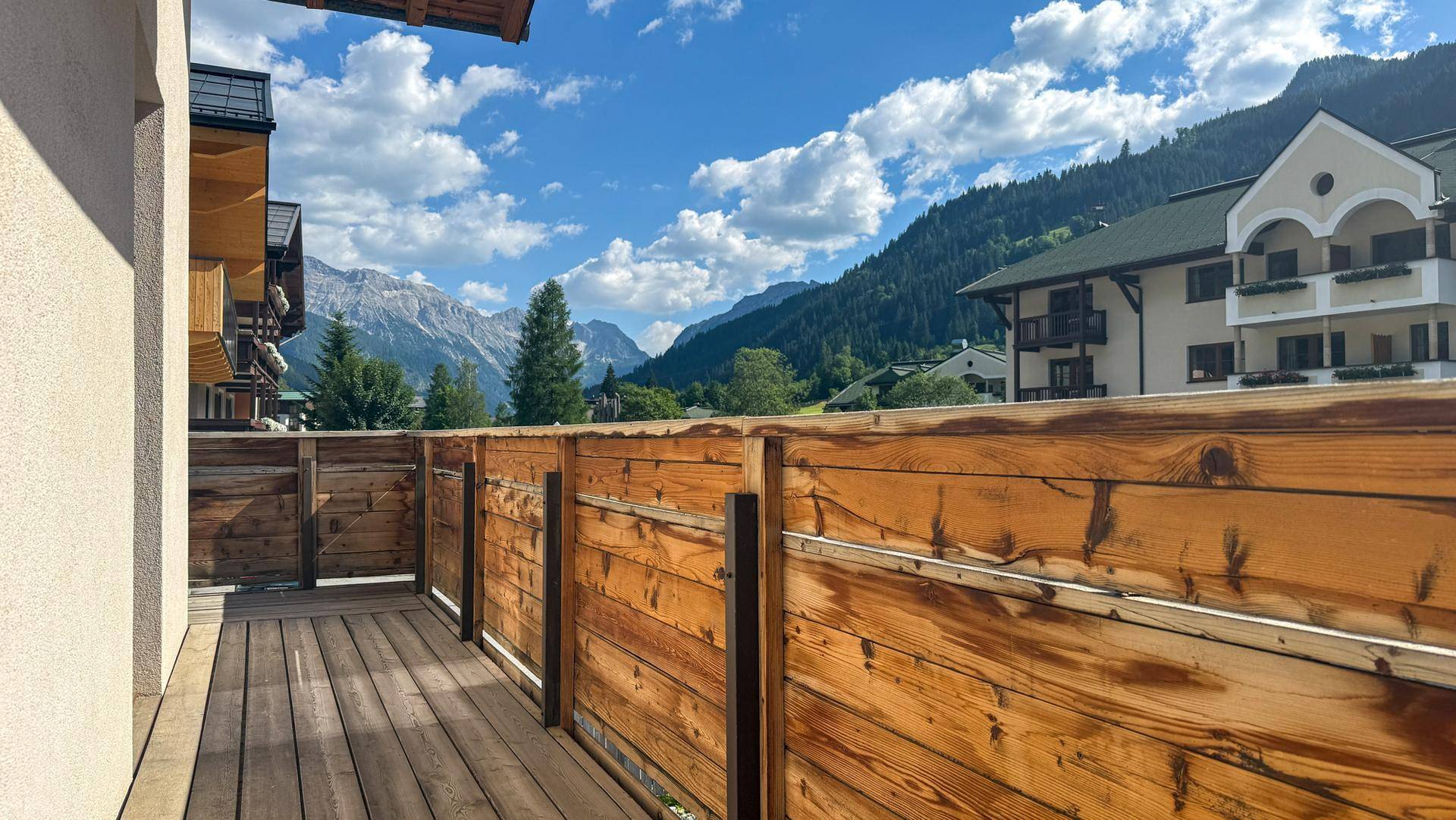 Balkon mit Holzboden und beeindruckendem Blick auf die umliegende Berglandschaft.