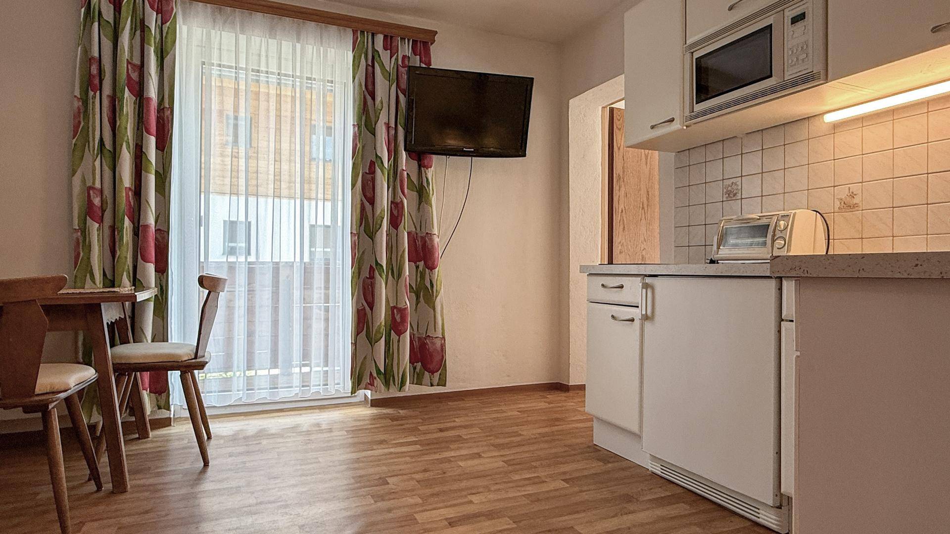 Kleine Küchenzeile mit Mikrowelle und Zugang zu einem Balkon.