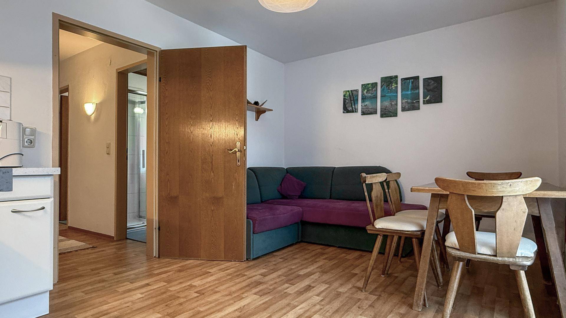 Wohnbereich mit Ecksofa, Esstisch und Zugang zu einem weiteren Zimmer.