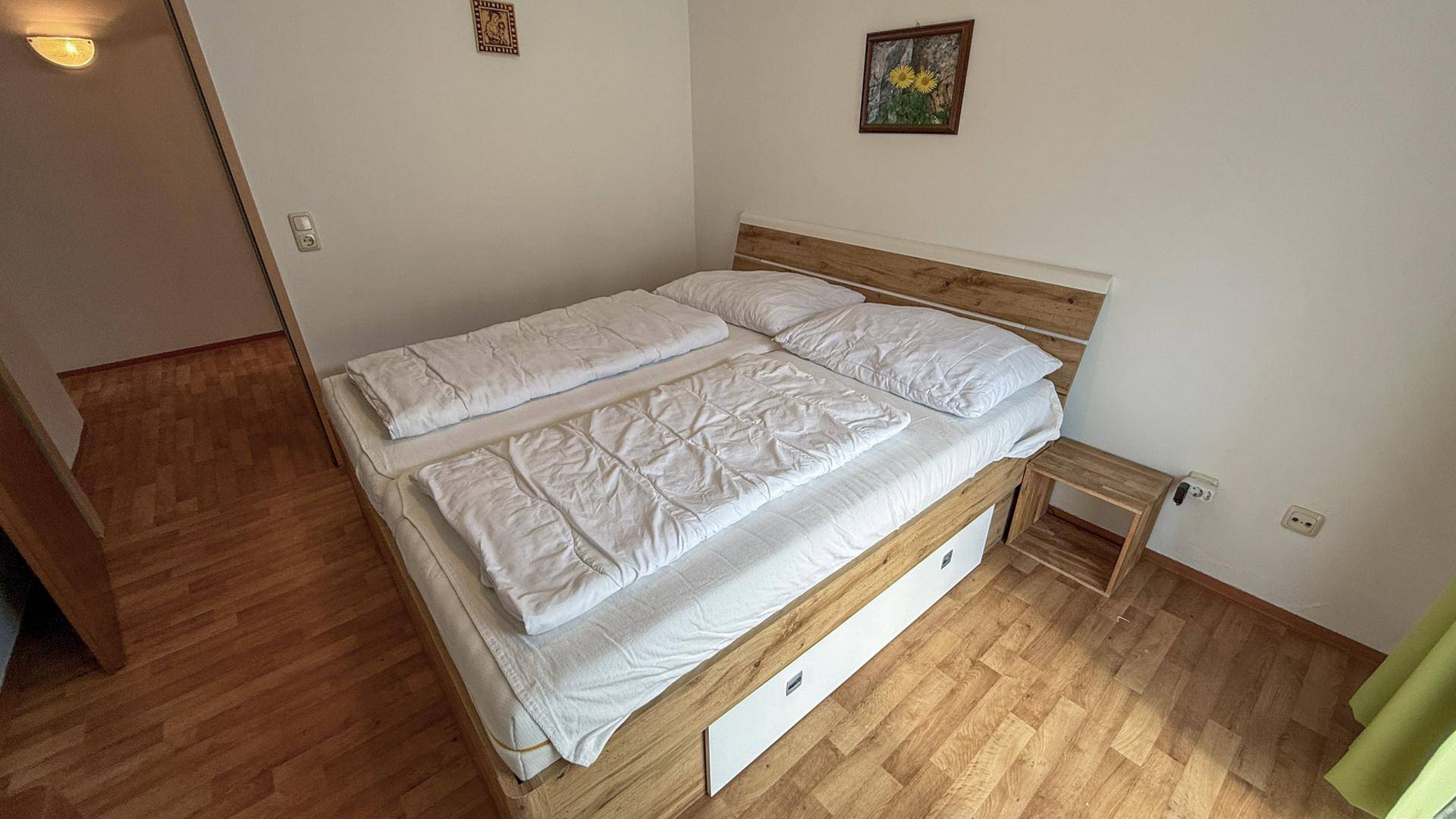 Helles Schlafzimmer mit komfortablem Doppelbett und kleinem Nachttisch, ideal für erholsame Nächte.