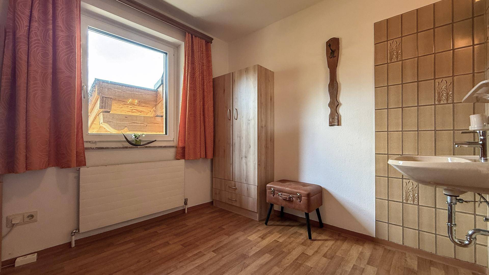 Raum mit Waschbecken, Holzschrank und Fenster, vielseitig nutzbar.