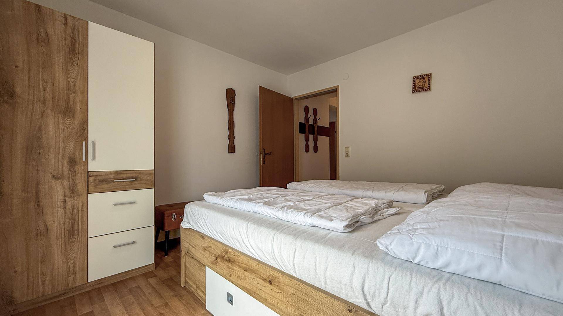 Schlafzimmer mit Doppelbett und einem praktischen Kleiderschrank aus Holz, gut beleuchtet.