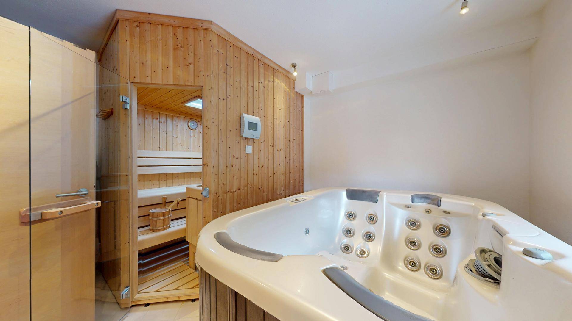 Privater Wellnessbereich mit Whirlpool und angrenzender Holzsauna für Entspannung.