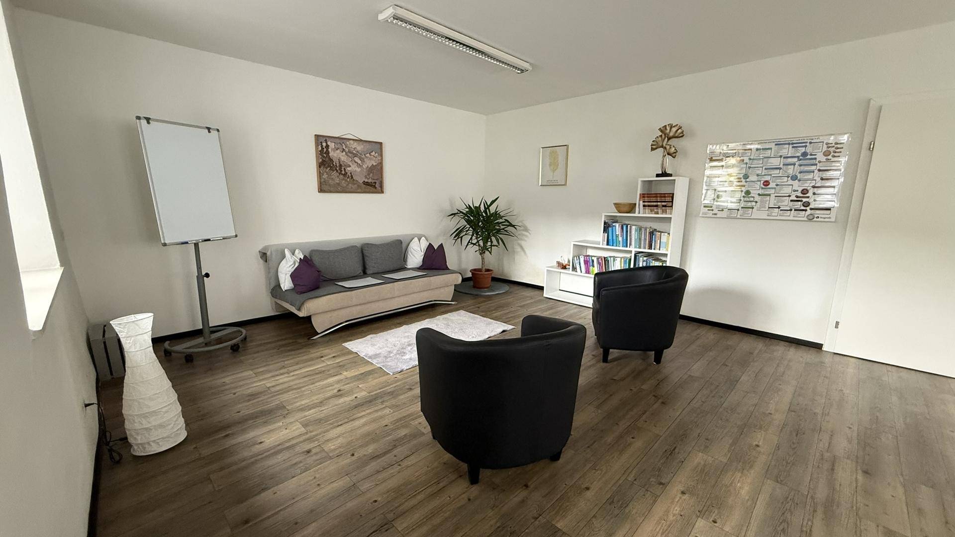 Geräumiger Büroraum mit Sitzgelegenheiten, Whiteboard und Bücherregal für flexible Nutzung.