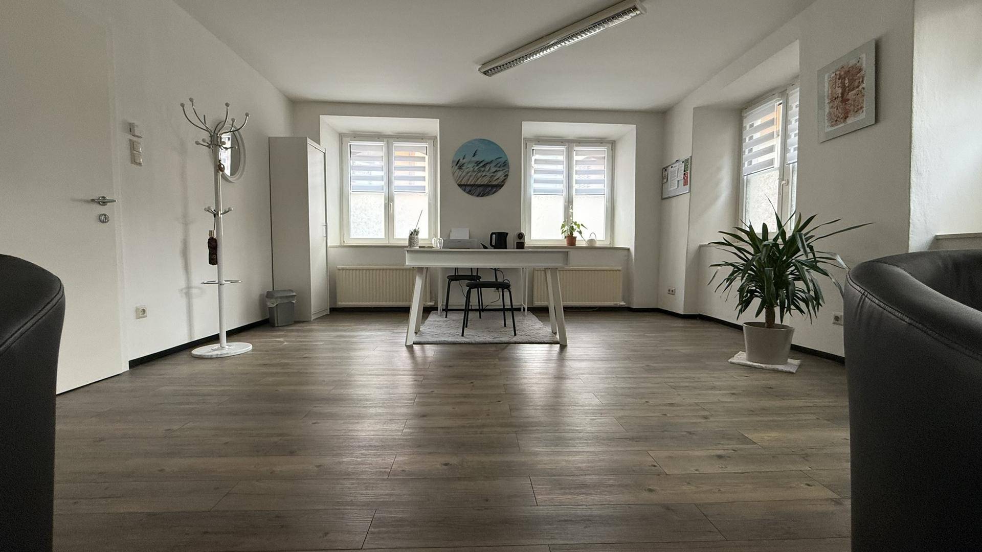 Weitläufiger Bürobereich mit Schreibtisch, mehreren Fenstern und viel Tageslicht.