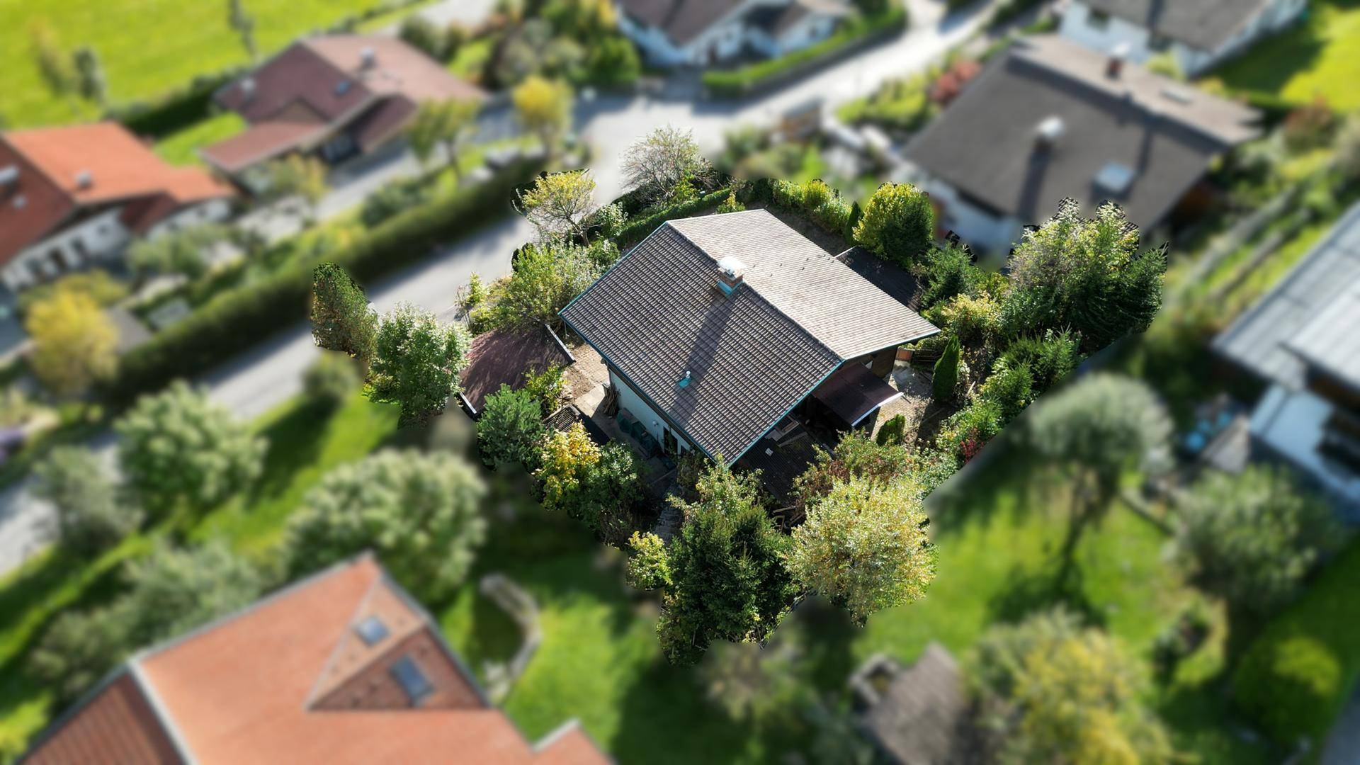 Luftaufnahme eines Einfamilienhauses mit Satteldach und großem Garten in einer Wohnsiedlung.