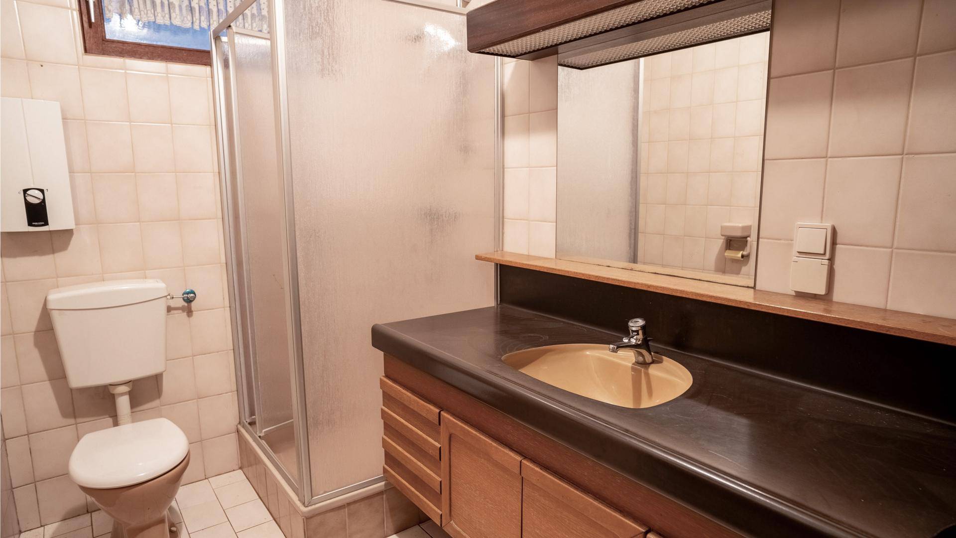 Funktionales Badezimmer mit Dusche, WC, Waschbecken und hellen Fliesen.
