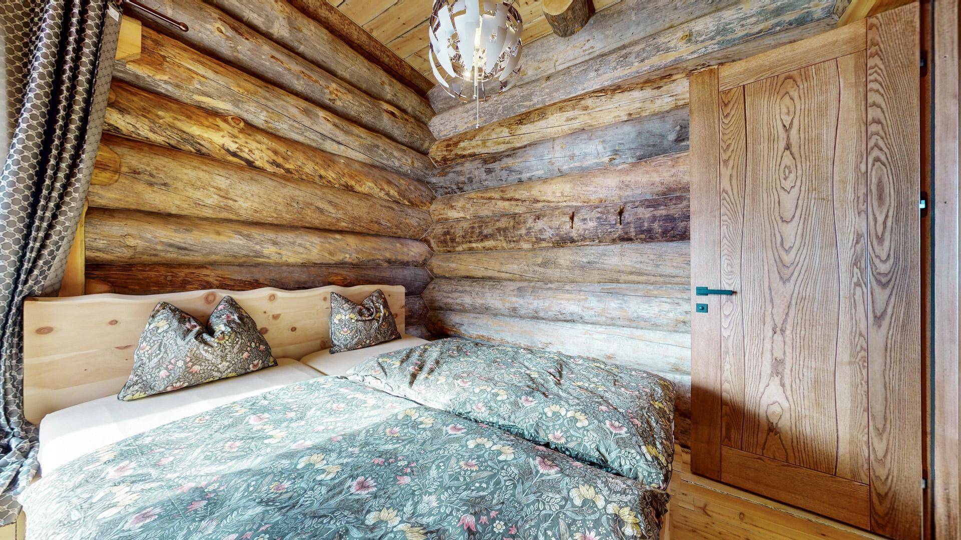 Schlafzimmer mit Holzwänden, Holzboden und einem bequemen Bett, das zum Entspannen einlädt.