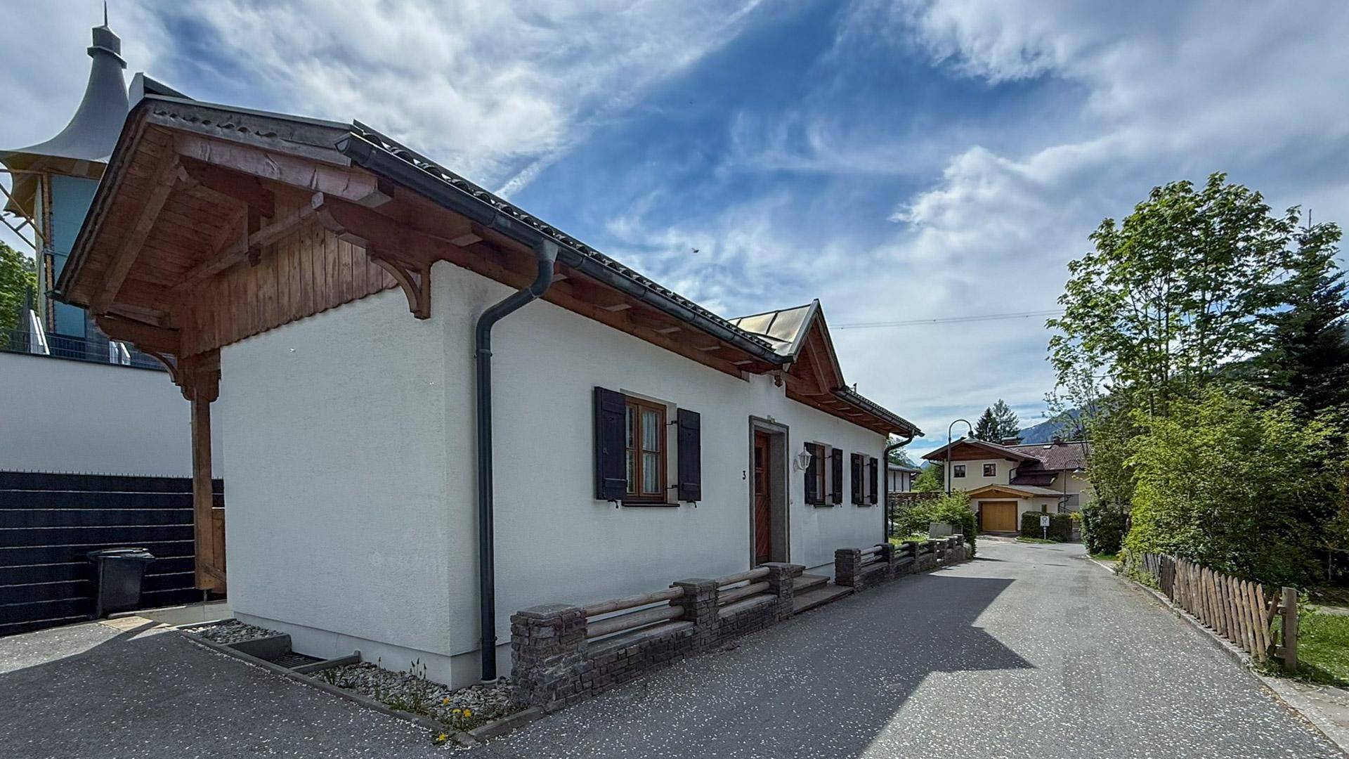 Seitenansicht des Hauses mit Zufahrt und Blick auf die umliegende Berglandschaft.