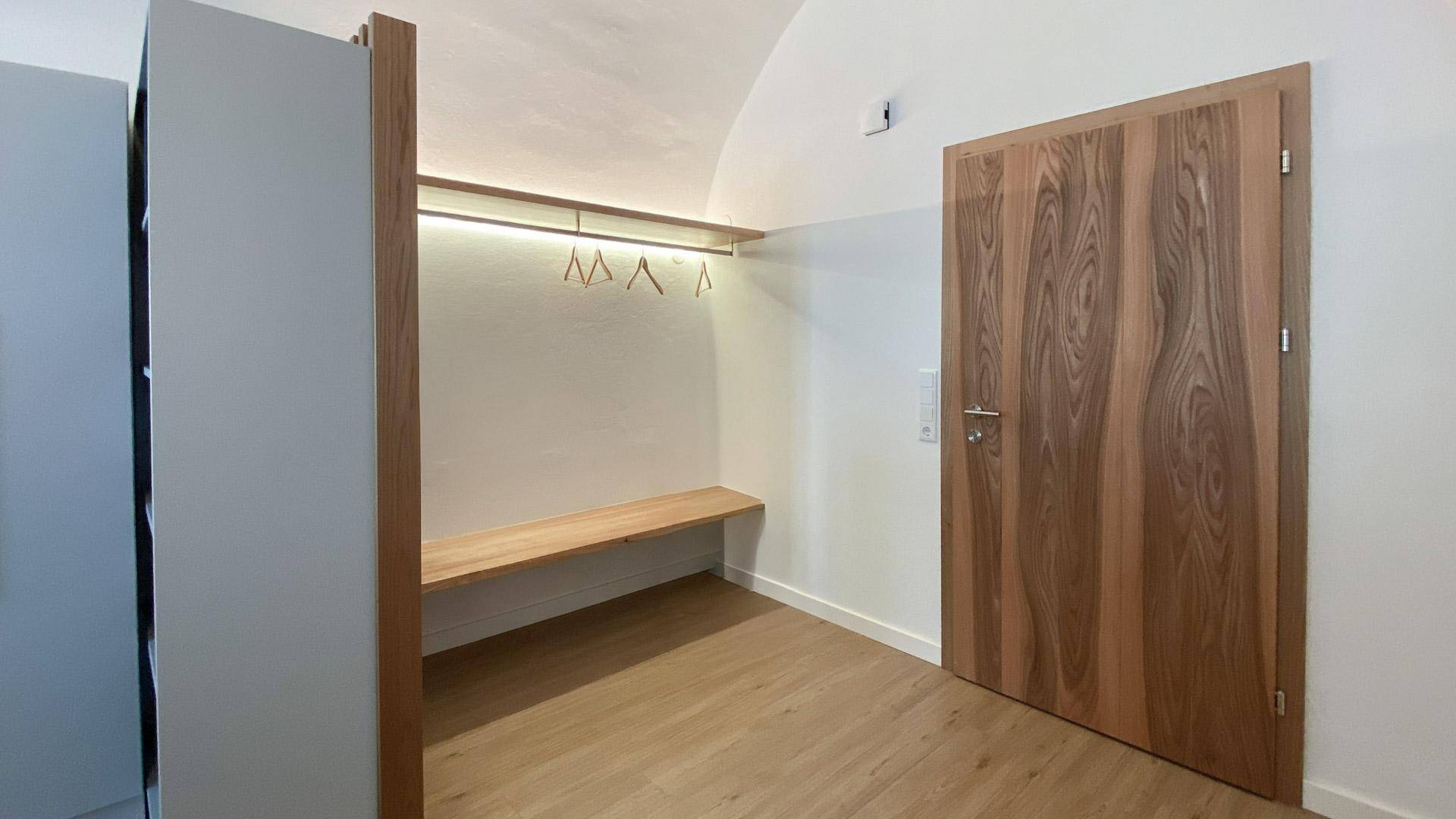 Eingangsbereich mit praktischer Garderobe, Sitzbank und einer stilvollen Holztür.