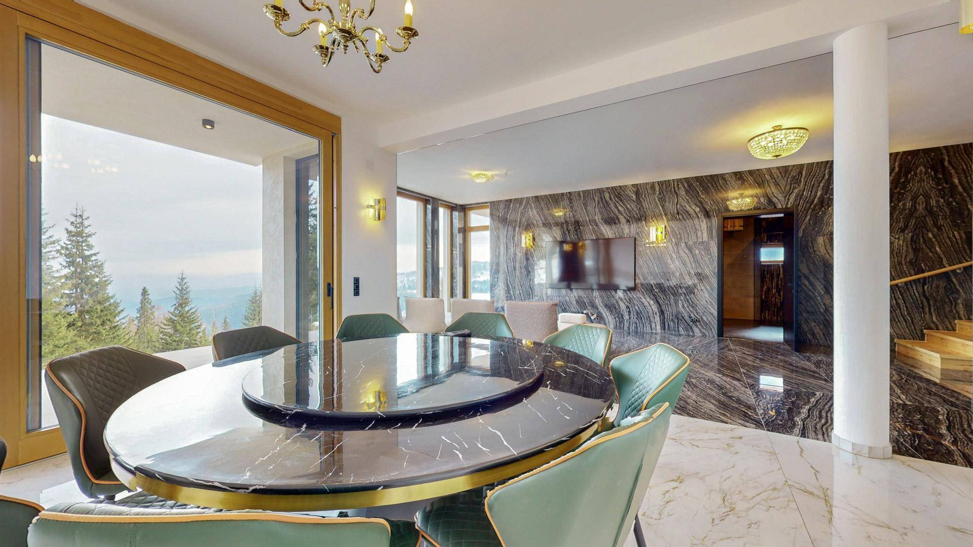 Eleganter Essbereich mit Marmortisch, luxuriösen Stühlen und Blick auf die umliegende Natur.