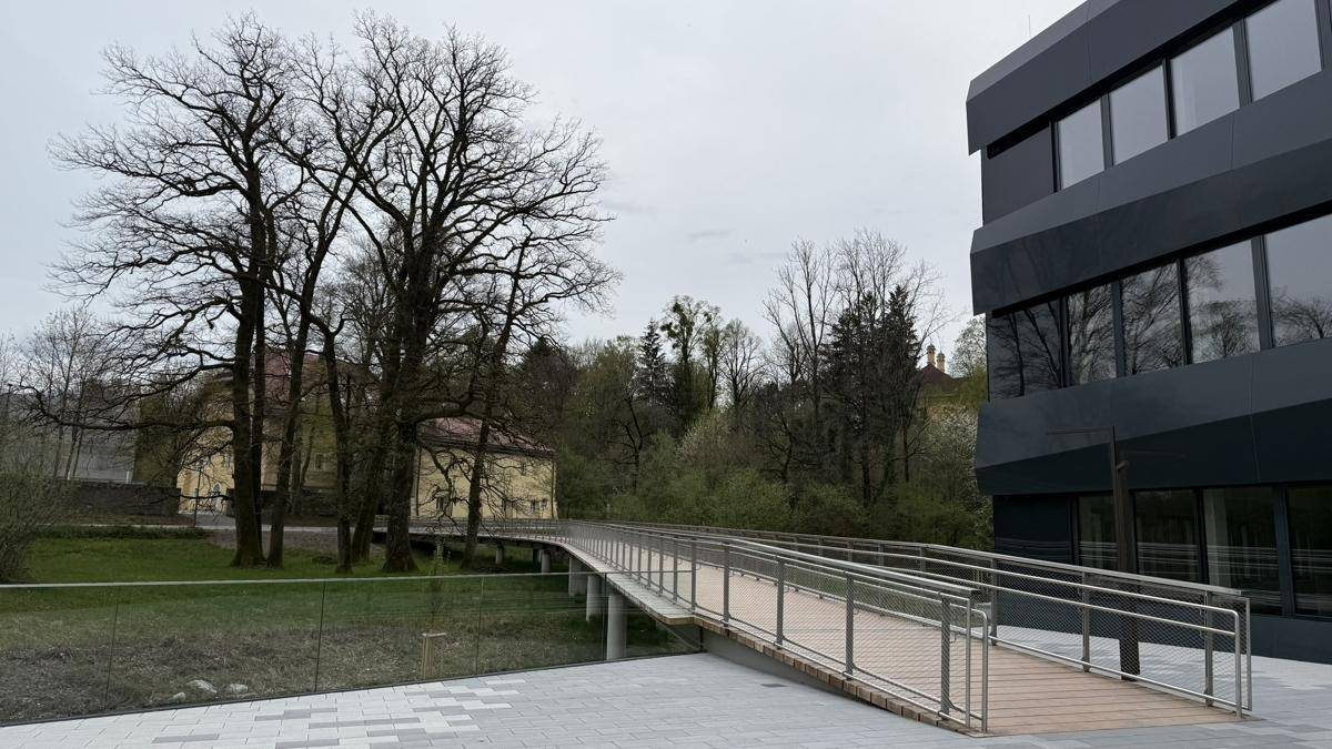 Außenbereich mit einer modernen Rampe, die zu einem Gebäude führt, umgeben von Bäumen und Grünflächen.