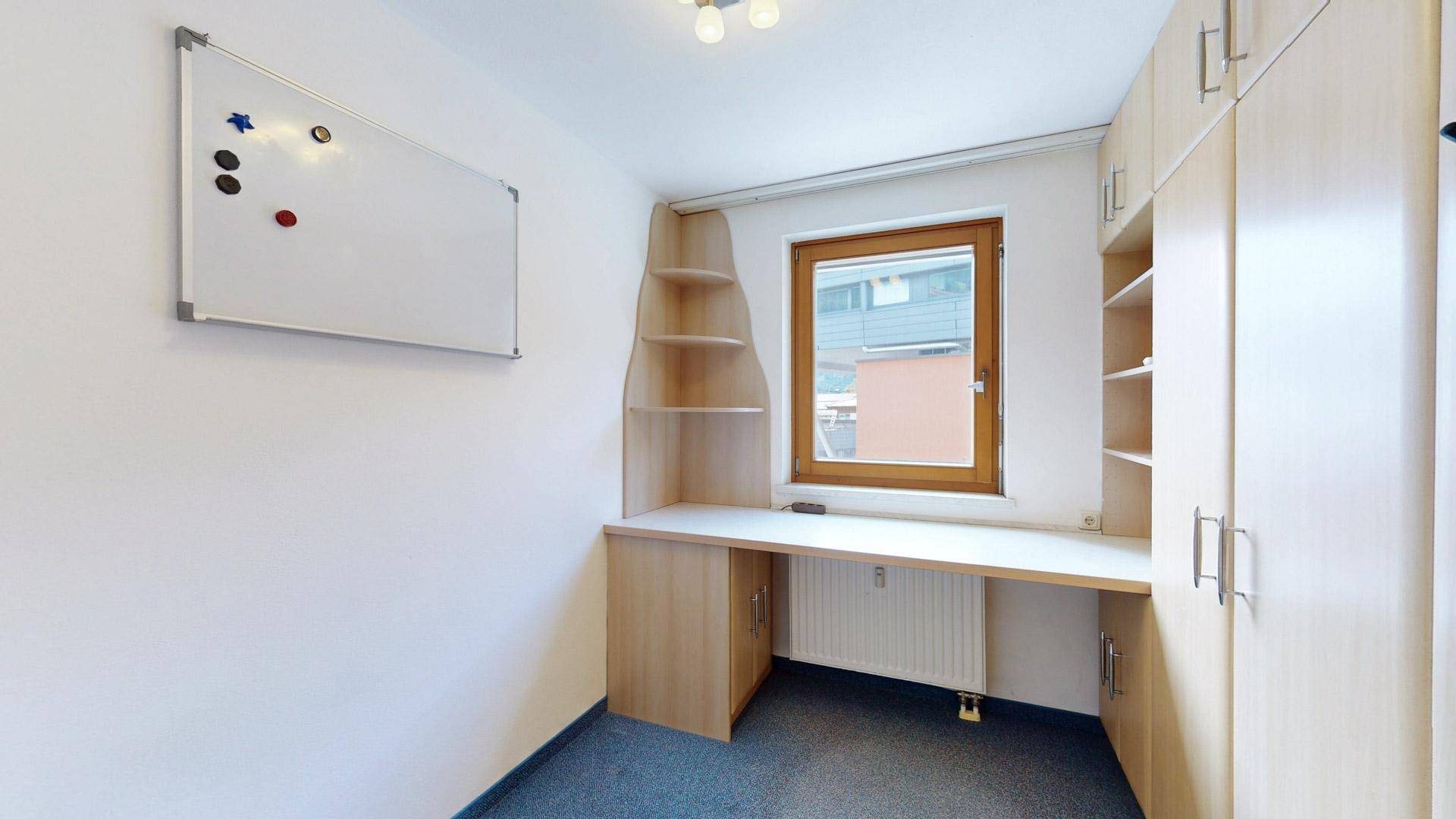 Arbeitszimmer mit Schreibtisch, integrierten Regalen und Whiteboard, ideal für Home-Office.