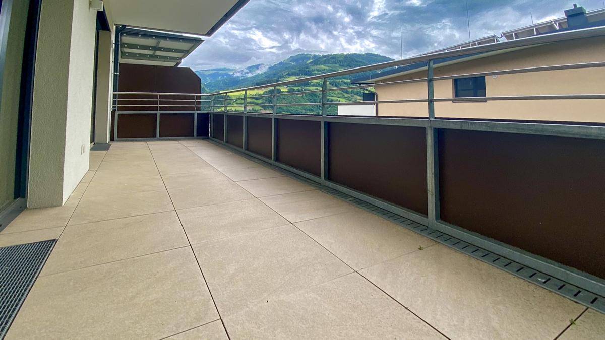 Breiter Balkon mit Fliesenboden und Panoramablick auf die grünen Berge und das Tal.