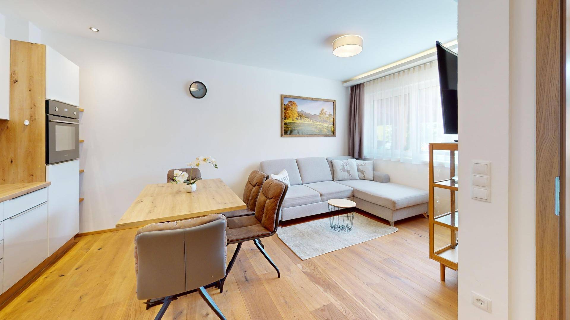 Offener Wohn-Essbereich mit moderner Küche, Sofa und Holzboden.