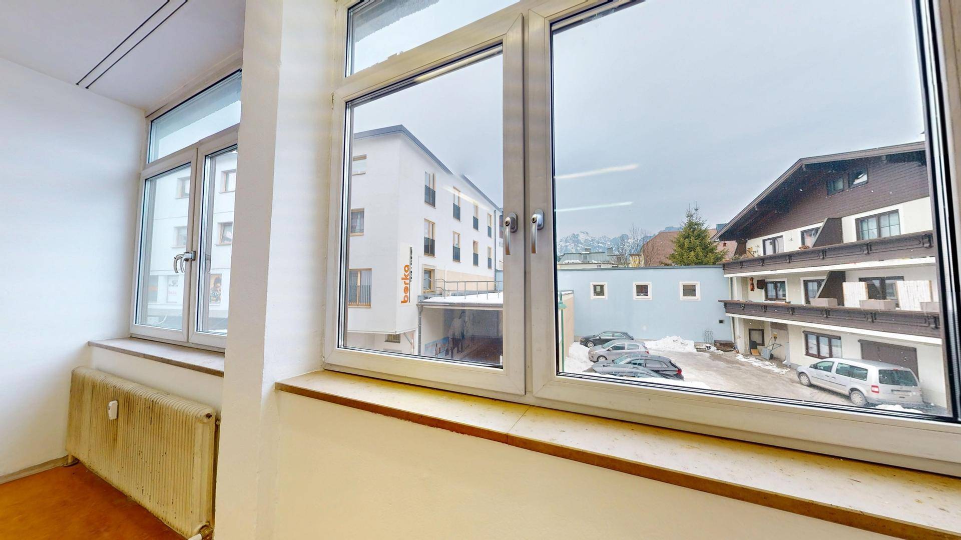 Blick aus dem Fenster eines Büros auf umliegende Gebäude und einen Parkplatz.