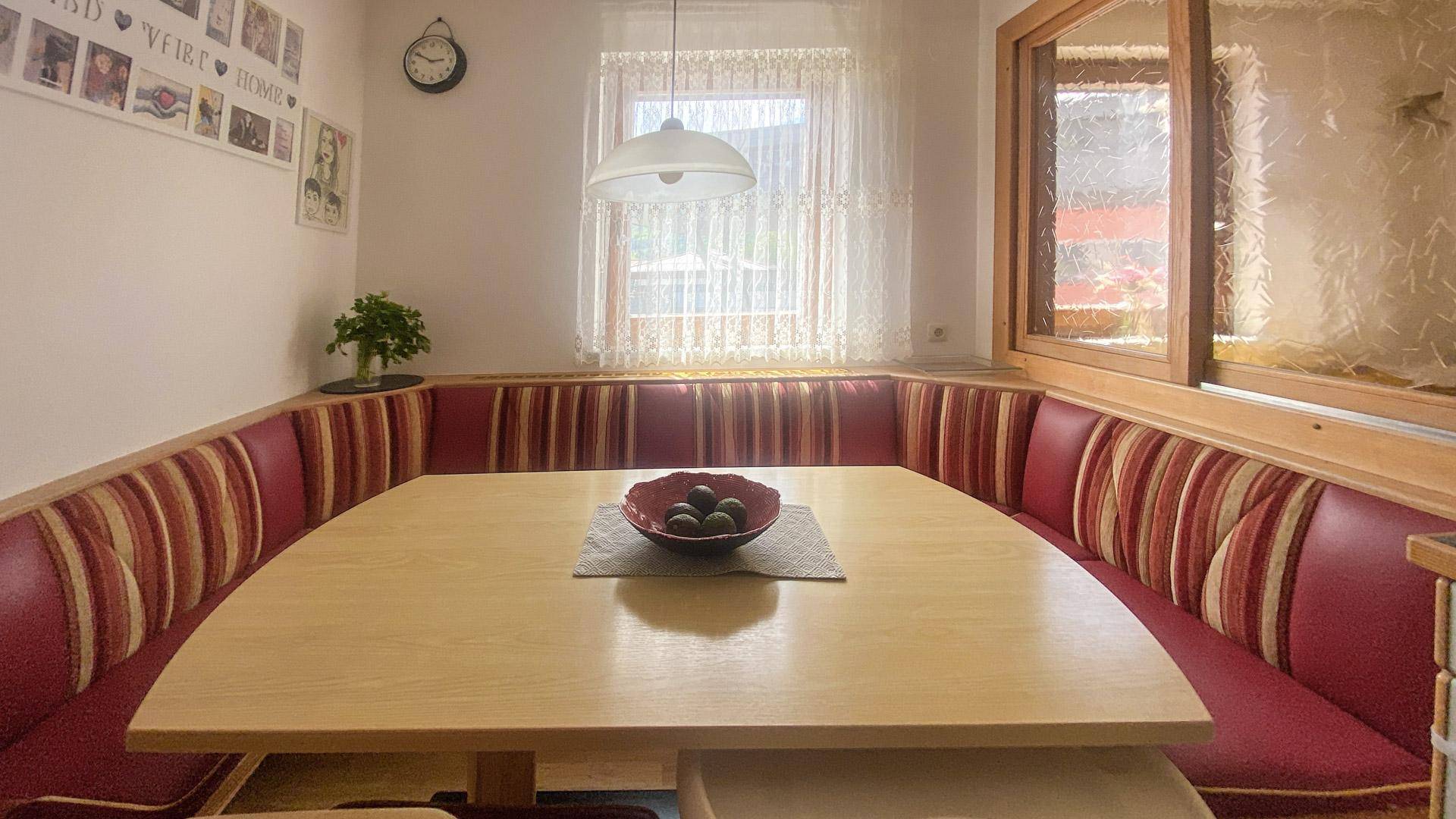 Gemütliche Essecke mit gepolsterter Sitzbank, Holztisch und Fensterblick.