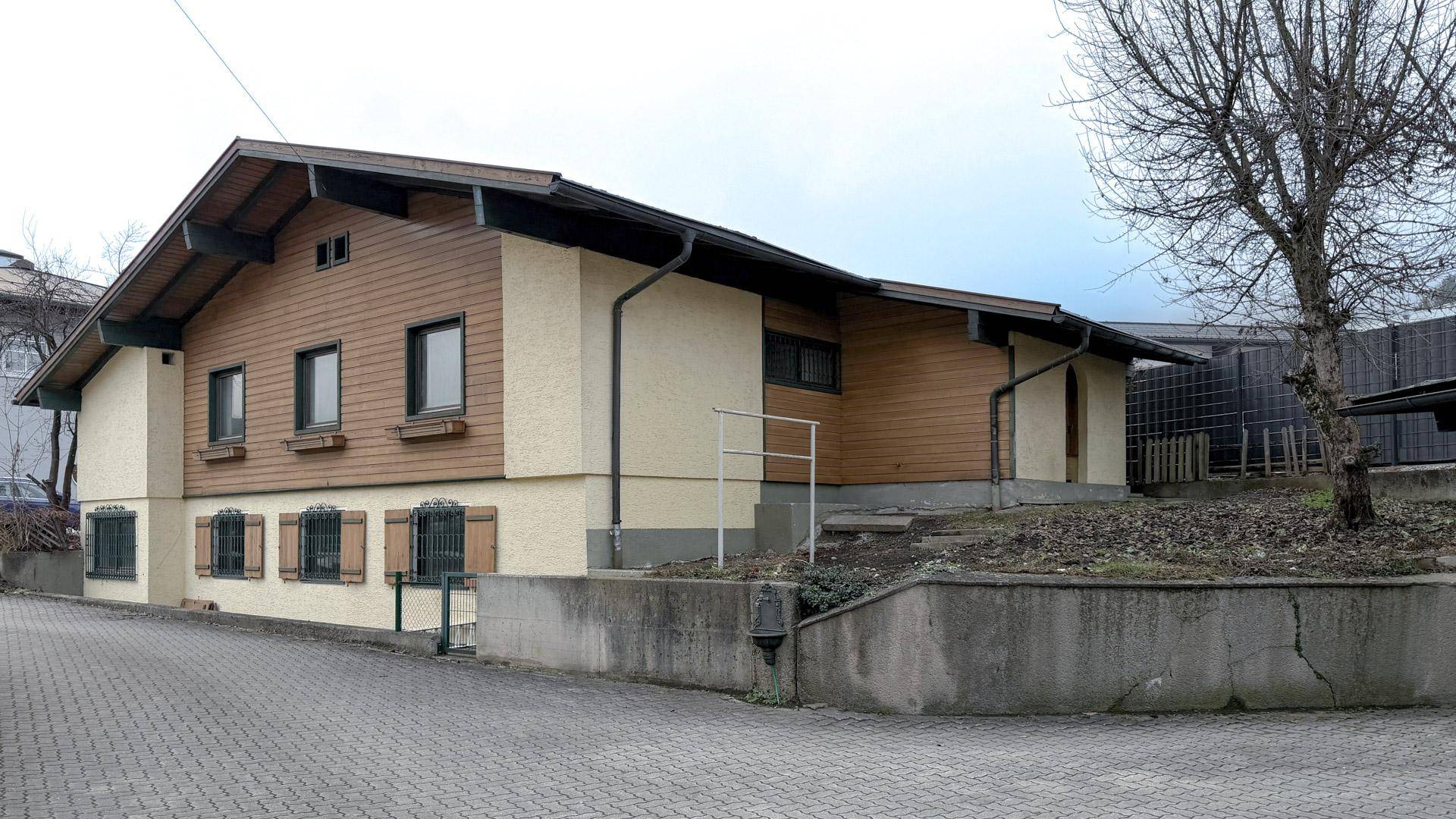 Rückansicht eines traditionellen Einfamilienhauses mit Holzverkleidung und Satteldach.
