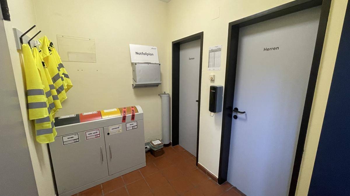 Funktionsraum mit Spinden, Sicherheitswesten und Türen zu den Toiletten, dient als Umkleidebereich.