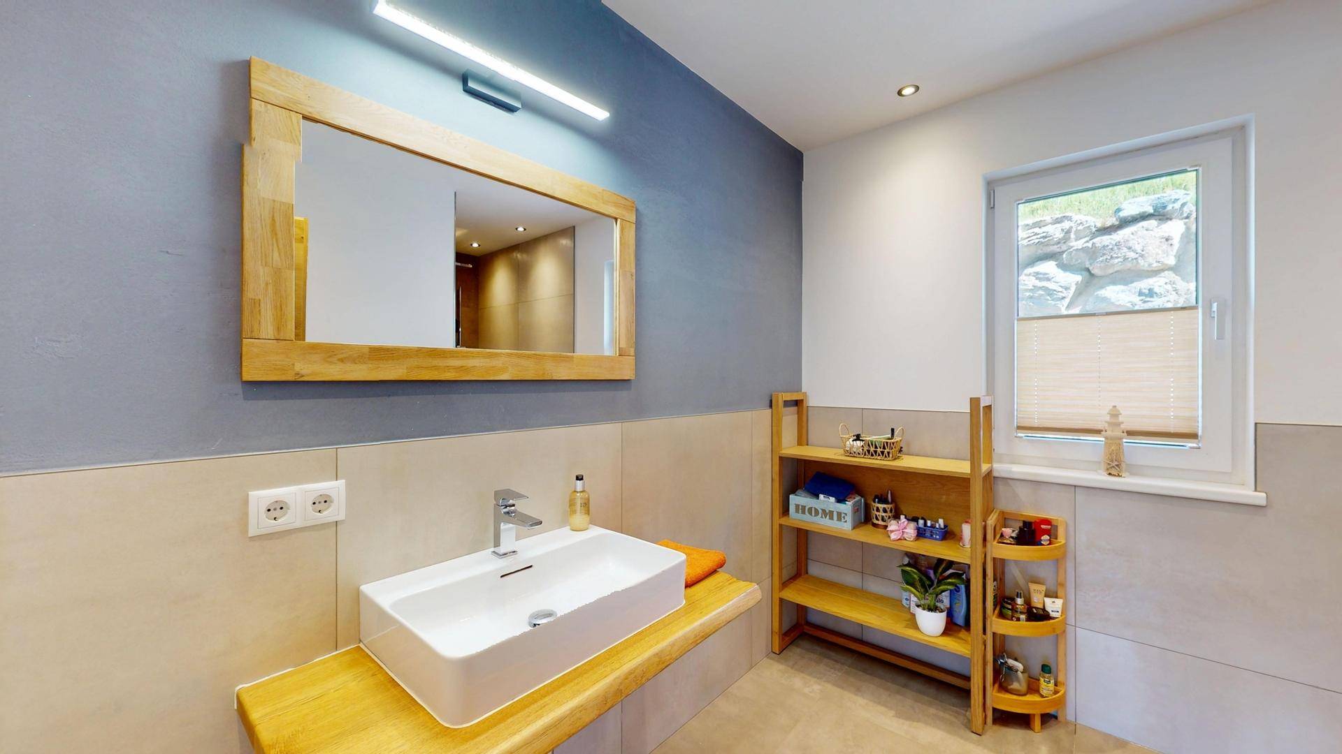 Modernes Badezimmer mit Einzelwaschbecken, Holzspiegel und hellen Fliesen.