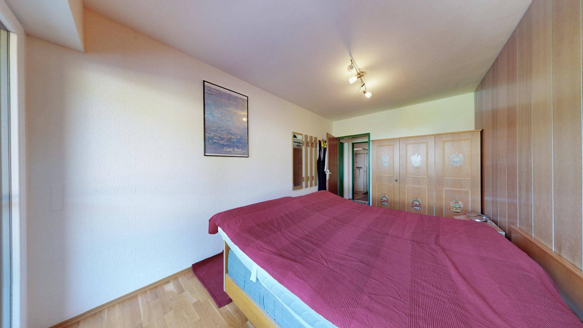 Schlafzimmer mit Holzboden, großem Bett und Einbauschränken.