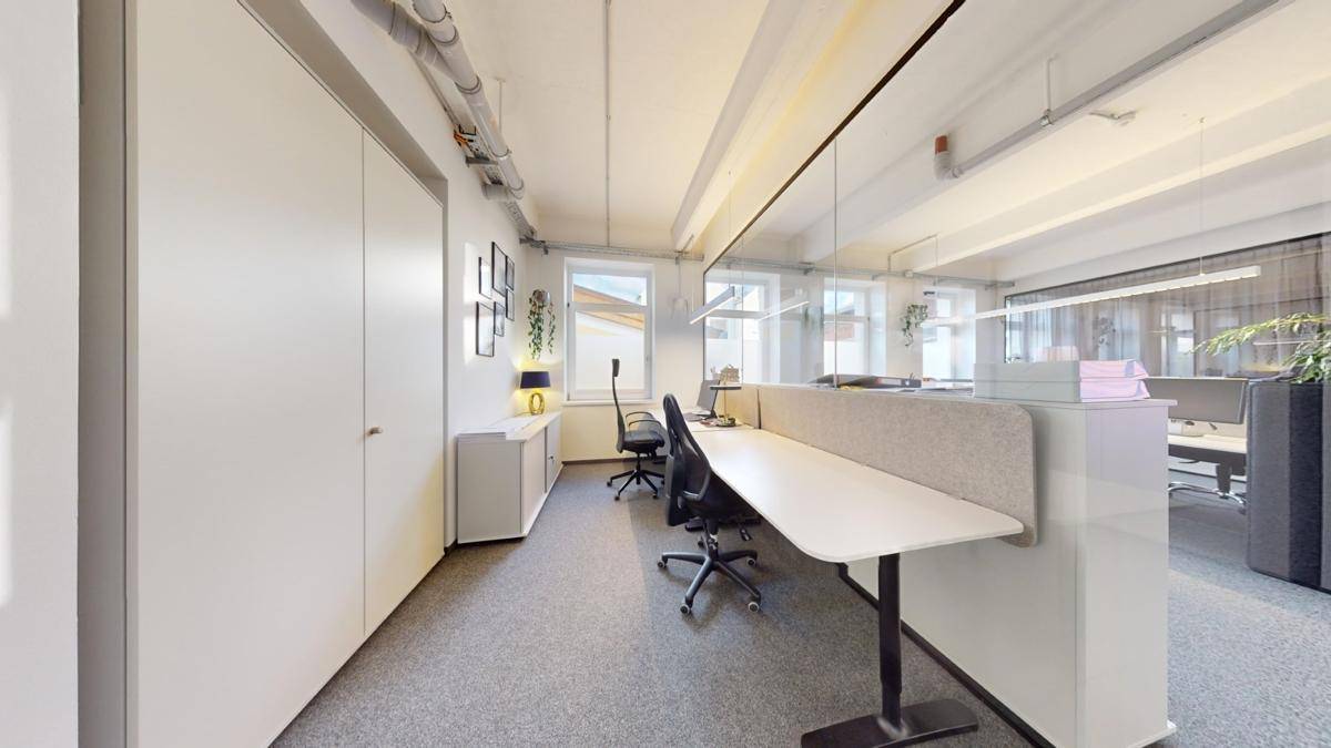 Funktionaler Bürobereich mit mehreren Arbeitsplätzen, Stauraum und Fenstern, die für ausreichend Tageslicht sorgen.