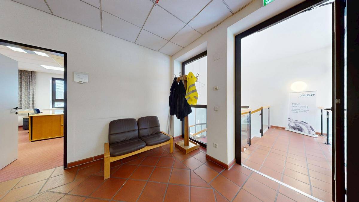 Flur mit Terrakotta-Fliesenboden, Garderobe und Blick auf den Treppenaufgang, der zu weiteren Etagen führt.