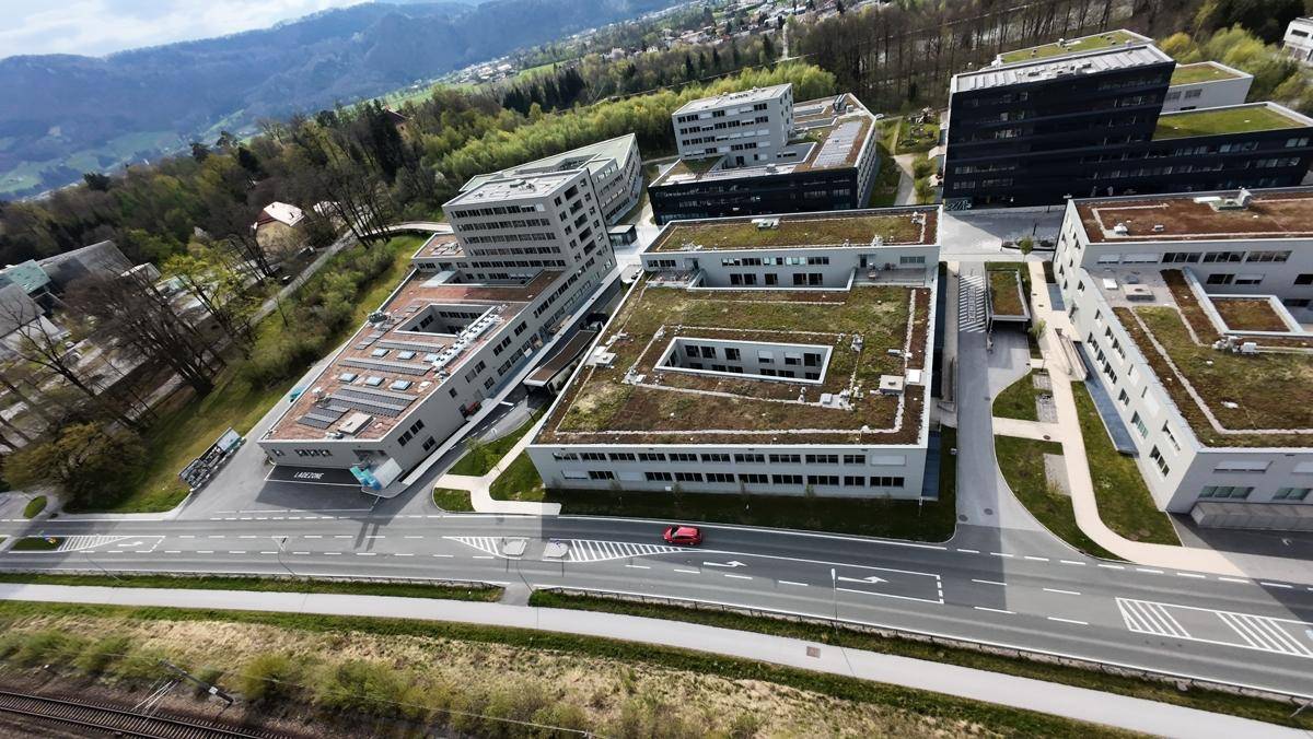 Weitläufige Luftaufnahme eines Geschäftsparks mit Gebäuden, Straßen und umliegender Natur.