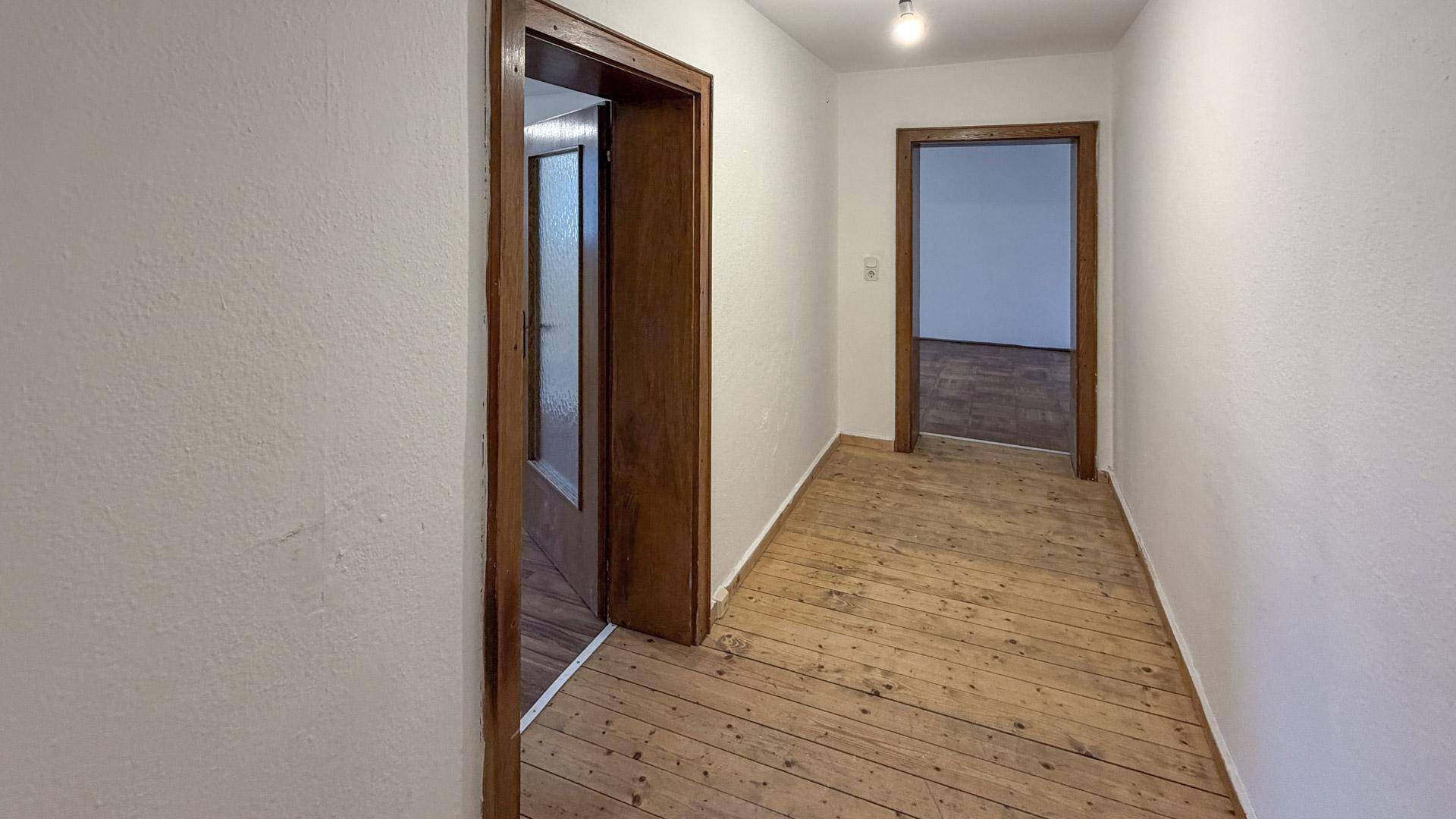 Heller Flur mit Holzboden und Holztüren, der zu verschiedenen Zimmern führt.