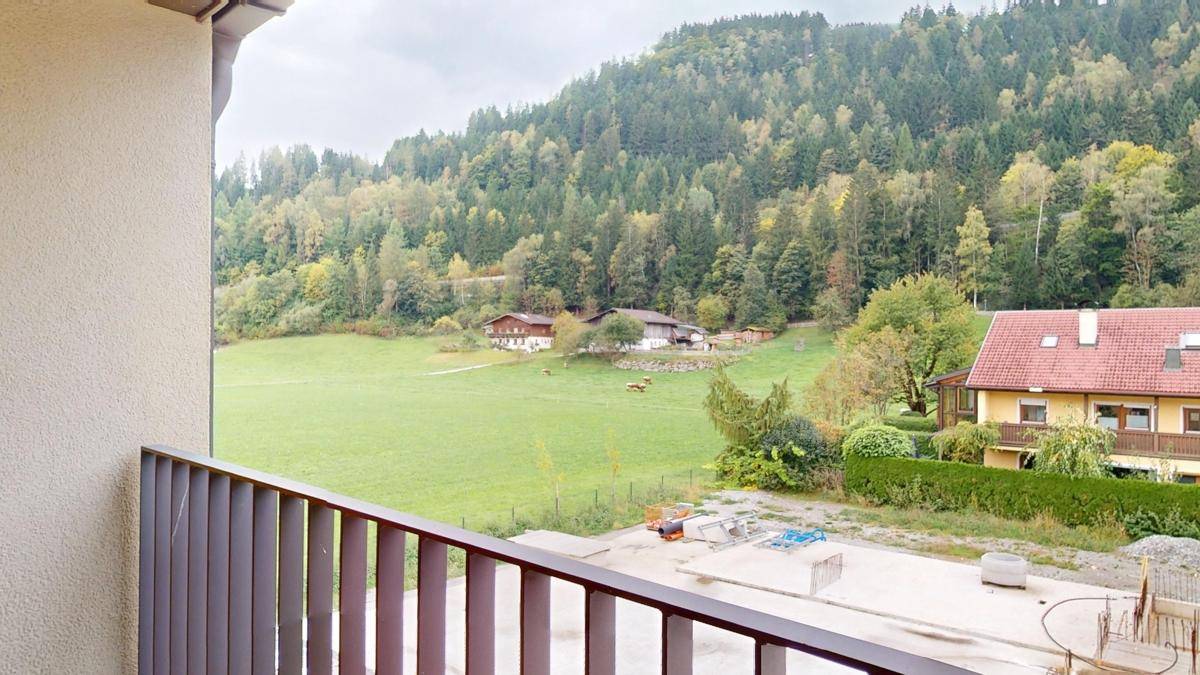 Balkon mit Panoramablick auf die umliegende Natur, grüne Wiesen und bewaldete Hügel.