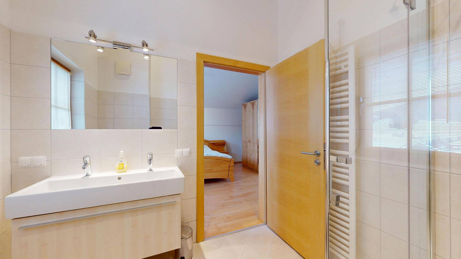 Helles Badezimmer mit Waschtisch, Spiegel und beheiztem Handtuchhalter.