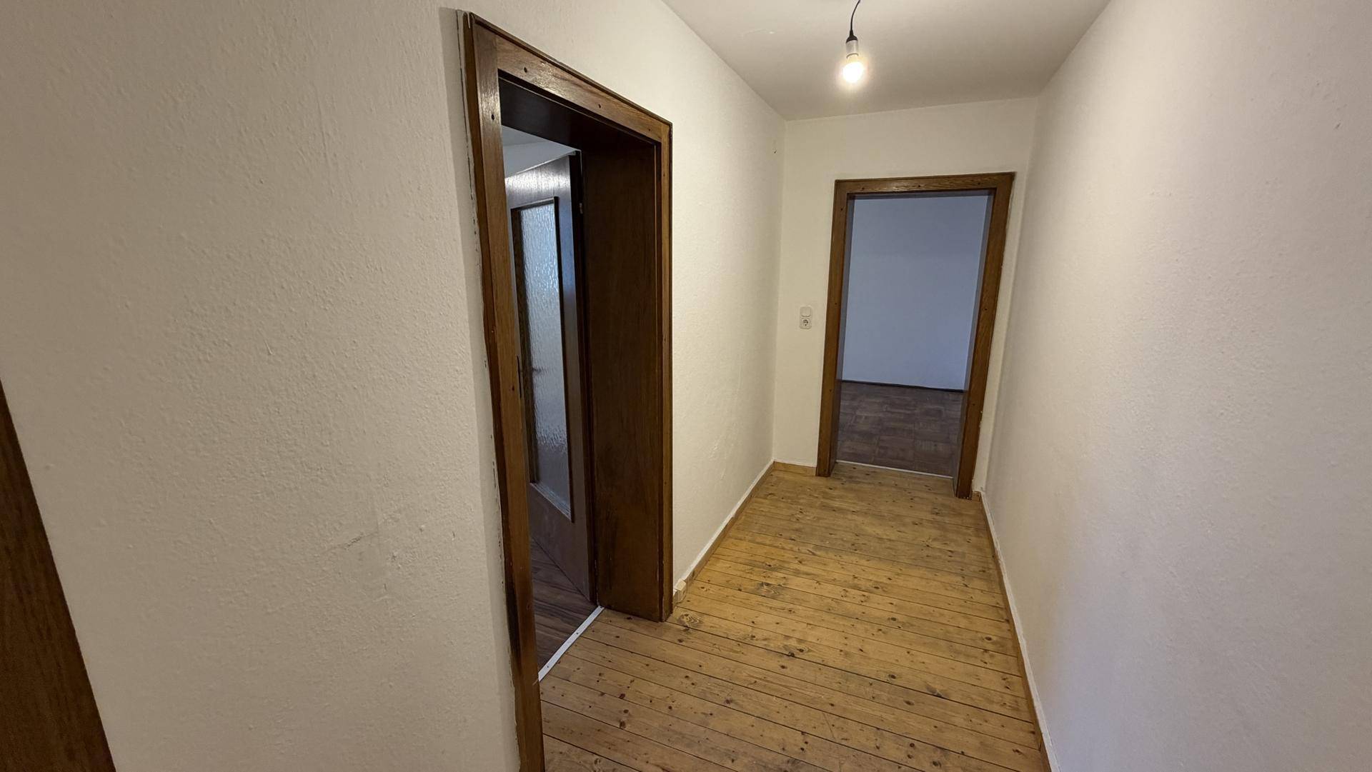 Flur mit Holzboden und mehreren Türen, verbindet verschiedene Zimmer.