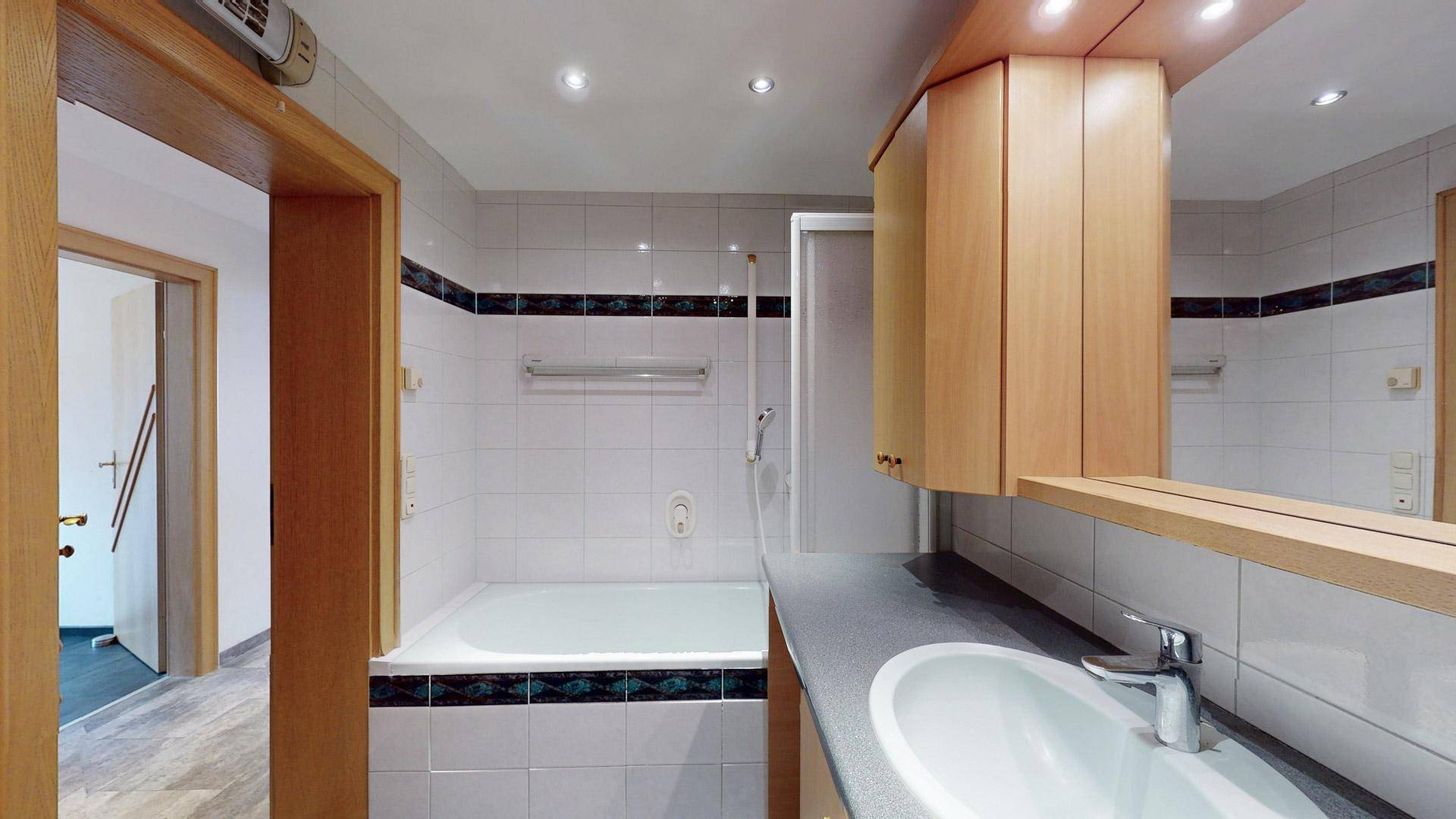 Helles Badezimmer mit Badewanne und Einzelwaschbecken, klassisch gefliest.