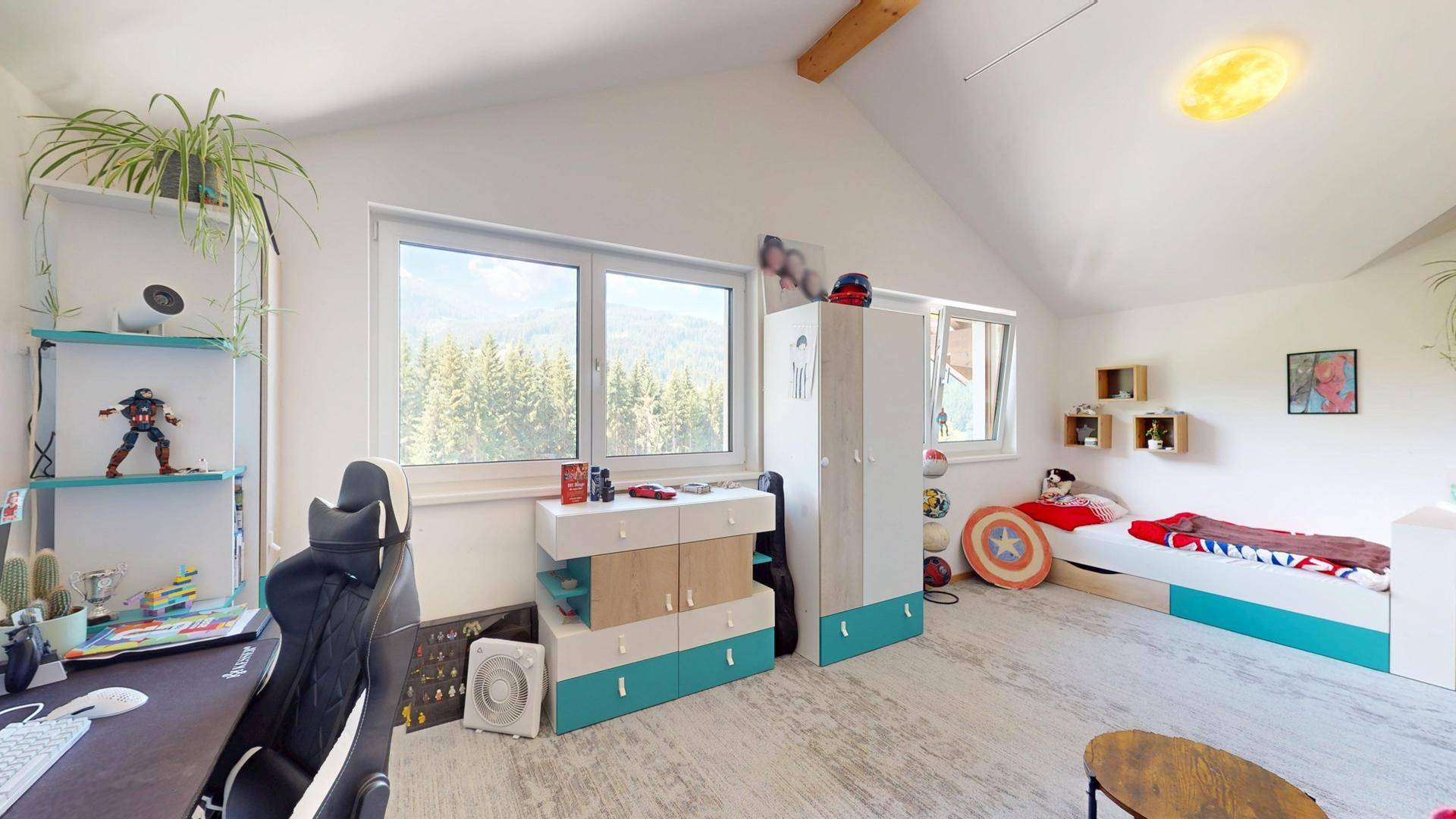 Helles Kinderzimmer mit Schreibtisch, Bett und Blick auf die Berge.